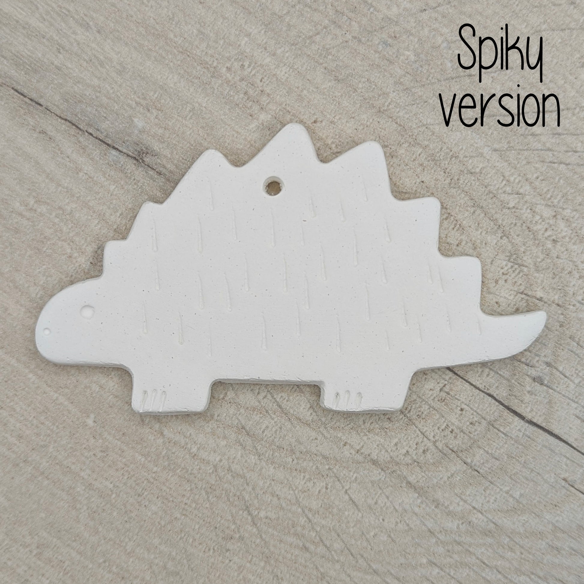 spiky Stegosaurus dinosaur air dried clay decoration, for children and adults to paint at home on wooden background