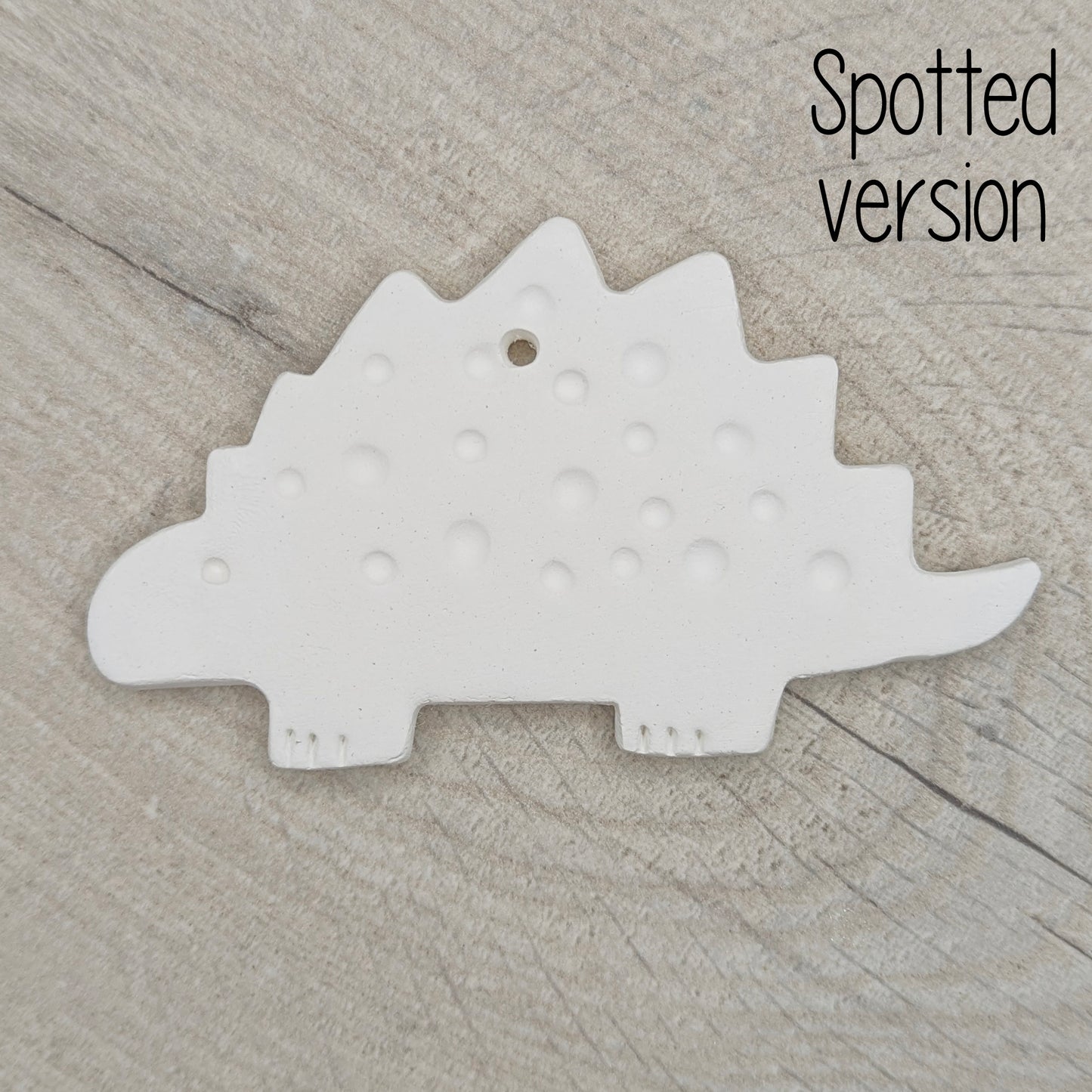 spotted Stegosaurus dinosaur air dried clay decoration on wooden background