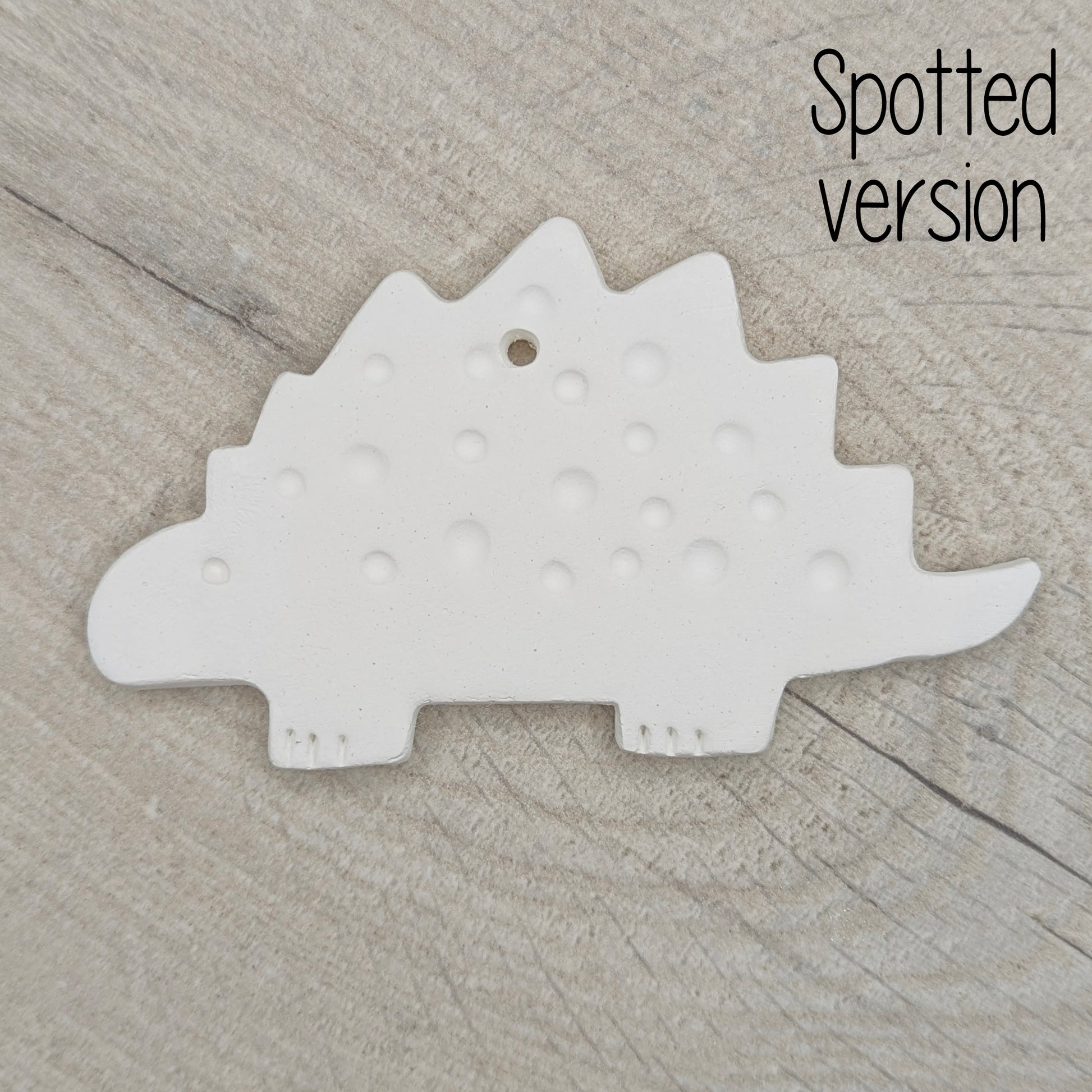 spotted Stegosaurus dinosaur air dried clay decoration on wooden background