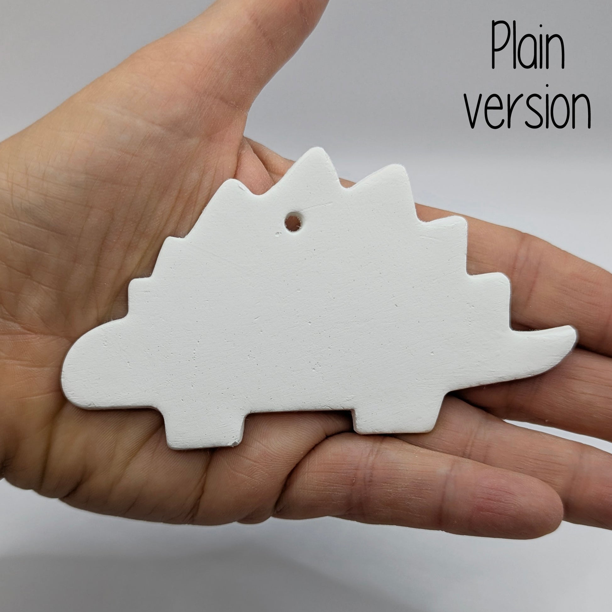 plain Stegosaurus dinosaur air dried clay decoration held in a hand for scale