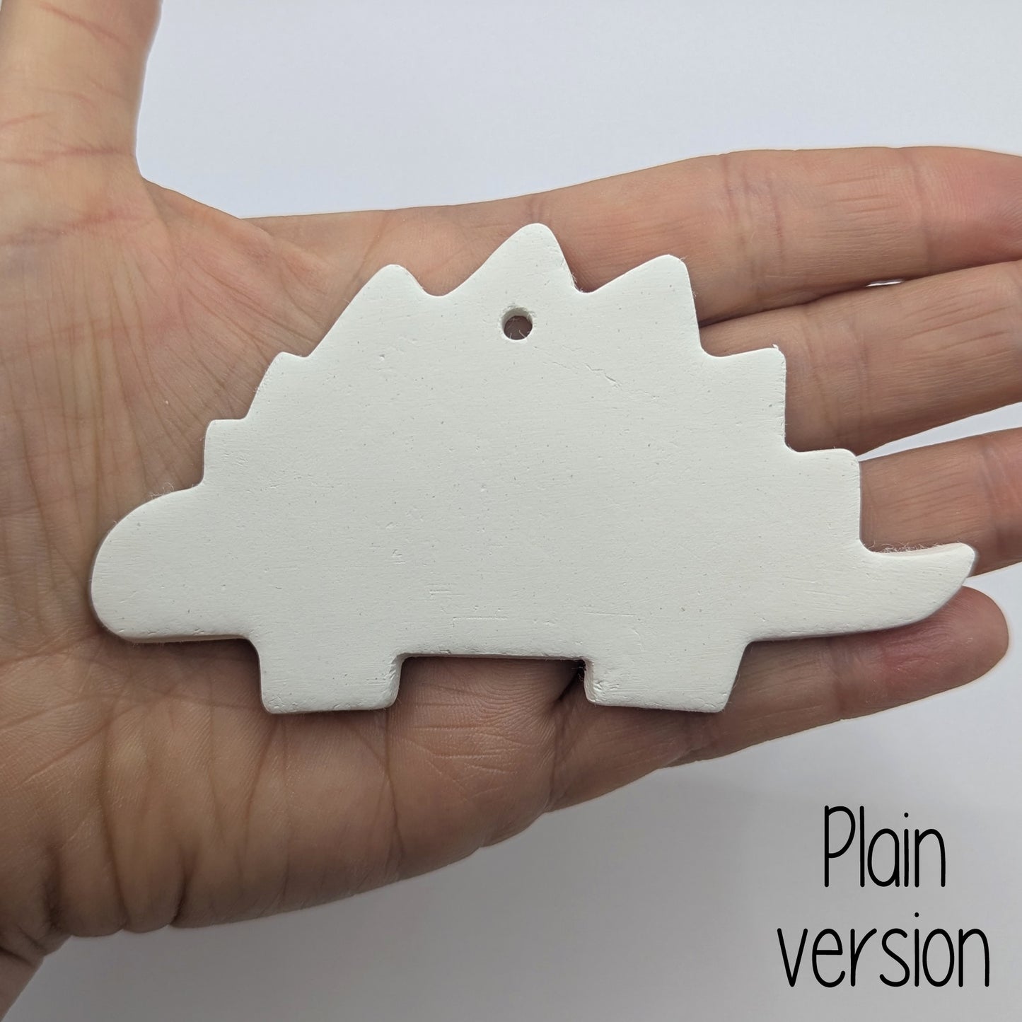 plain Stegosaurus dinosaur clay decoration, shown in ladies hand for scale