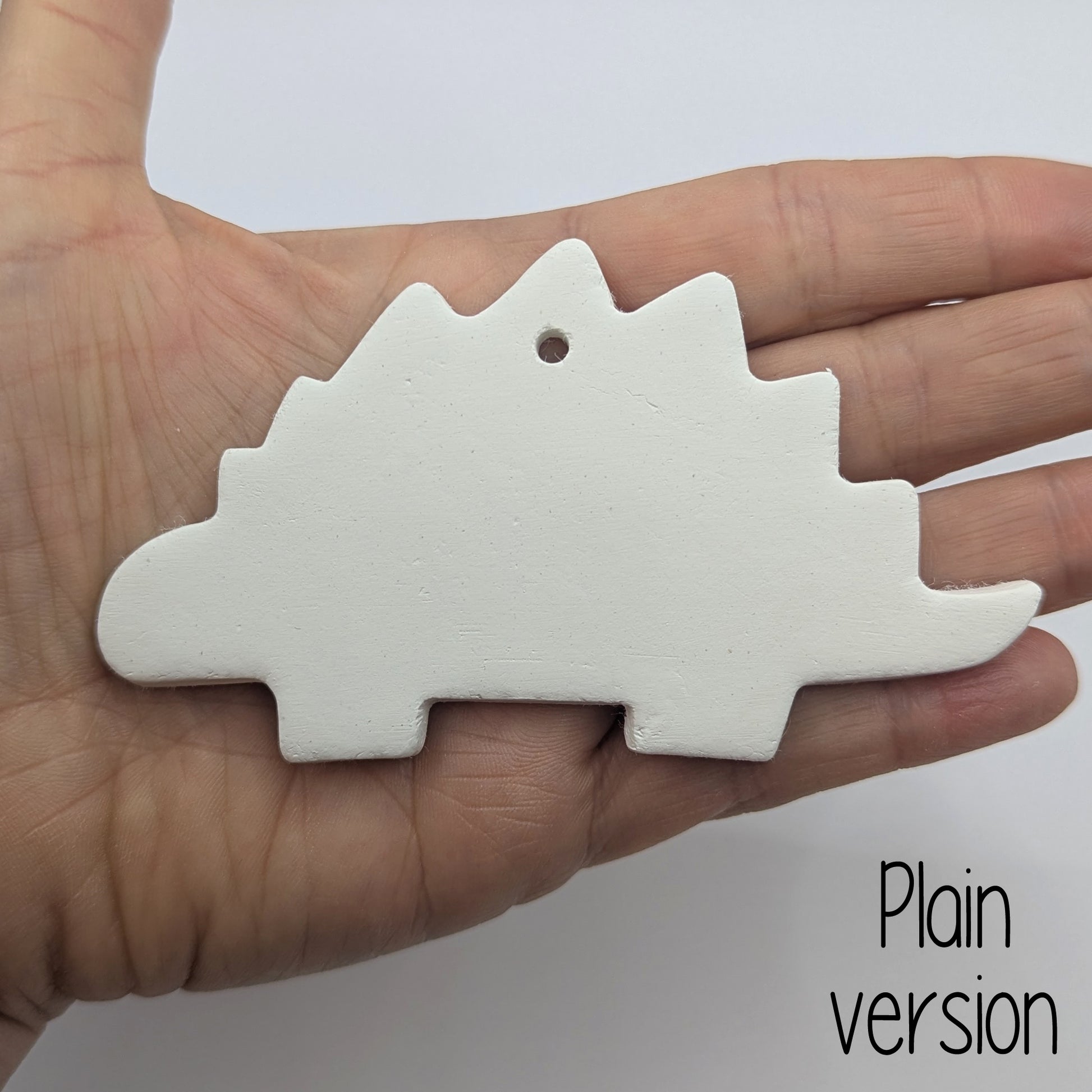 plain Stegosaurus dinosaur clay decoration, shown in ladies hand for scale