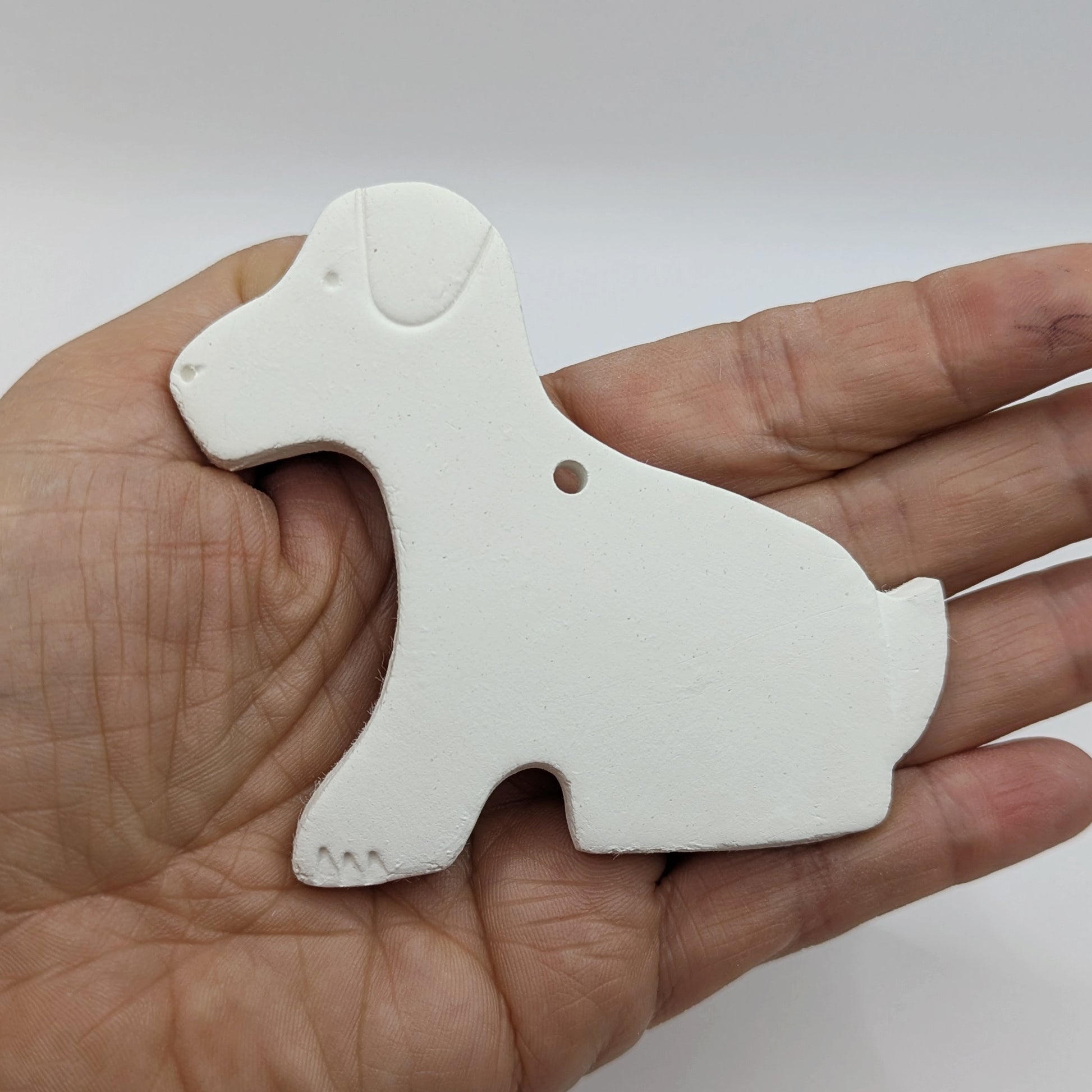White clay Labrador sitting dog shape, held in hand
