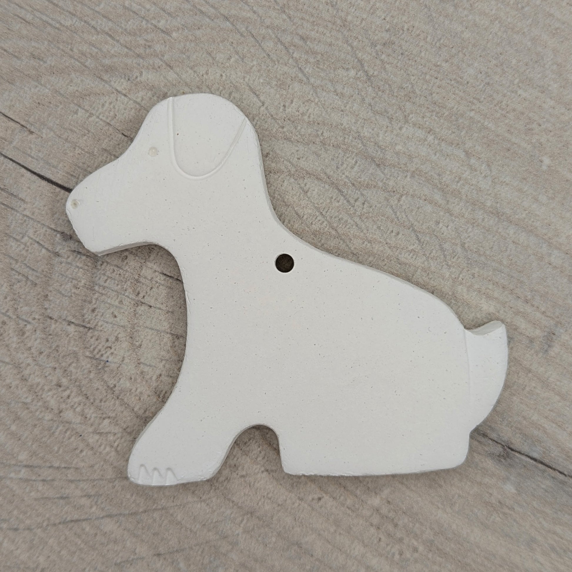 White clay Labrador sitting dog shape on a wooden surface