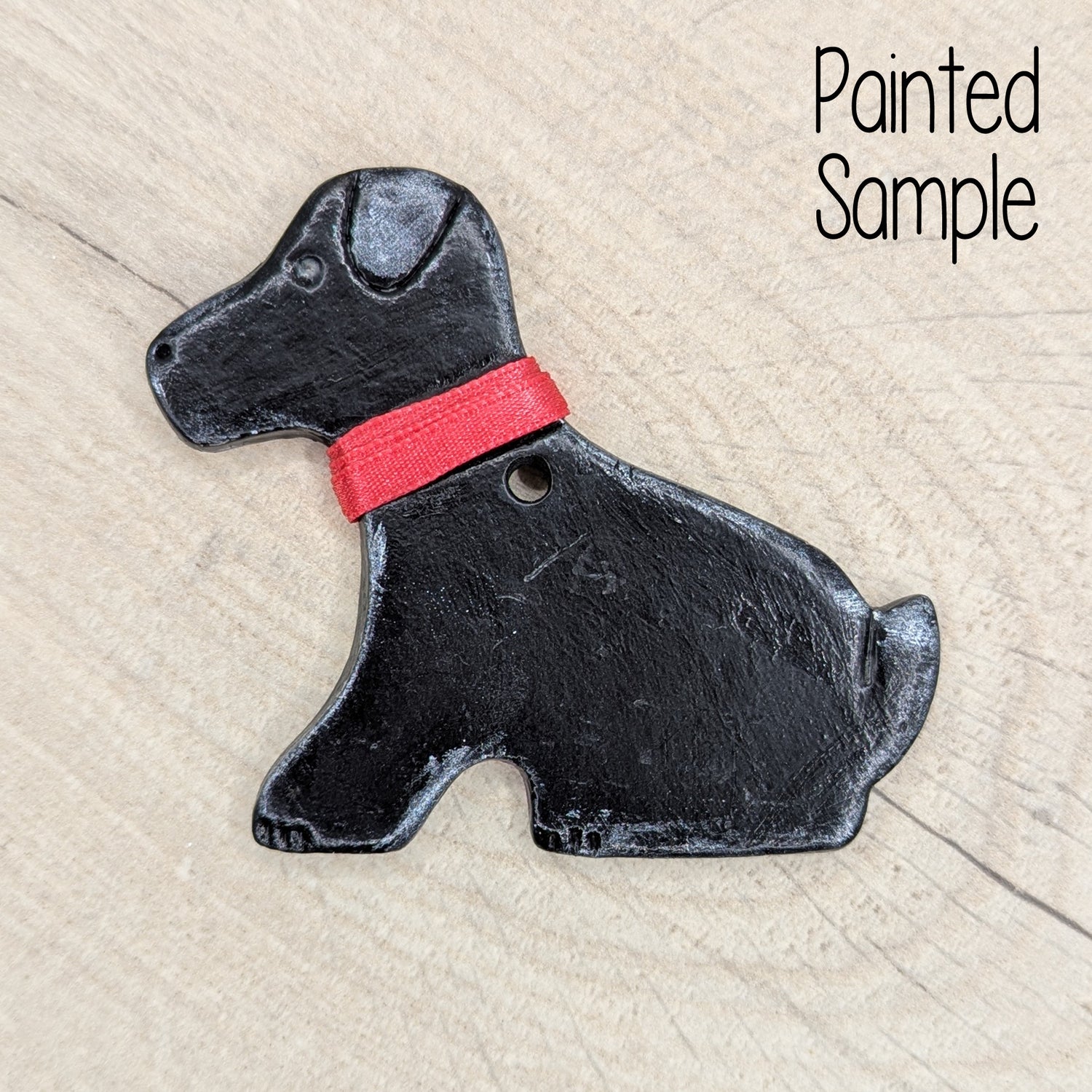 clay decoration of a Labrador dog painted to look like a black labrador with a red ribbon collar
