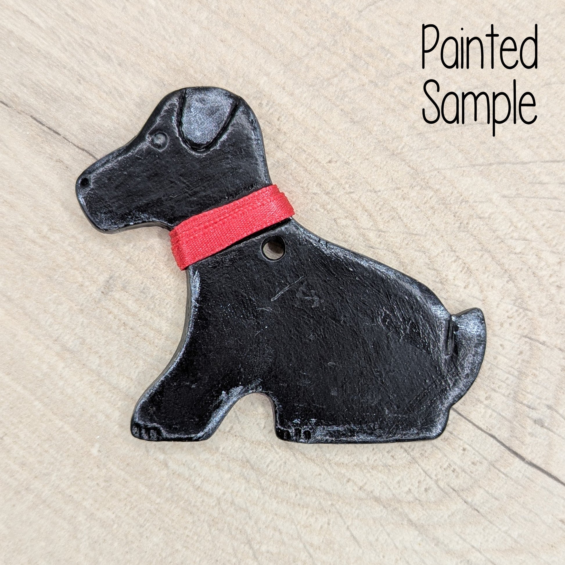 clay decoration of a Labrador dog painted to look like a black labrador with a red ribbon collar