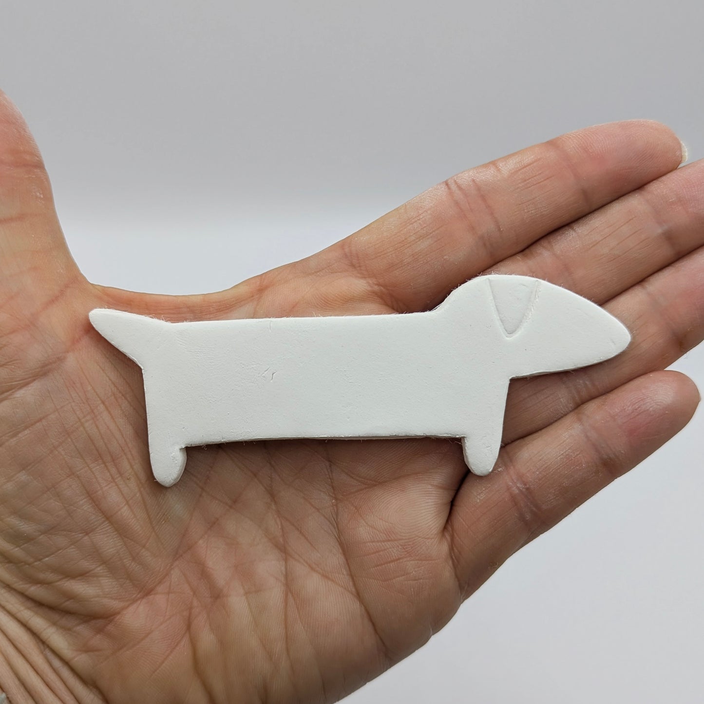 sausage clay decoration shown in palm of hand to show scale