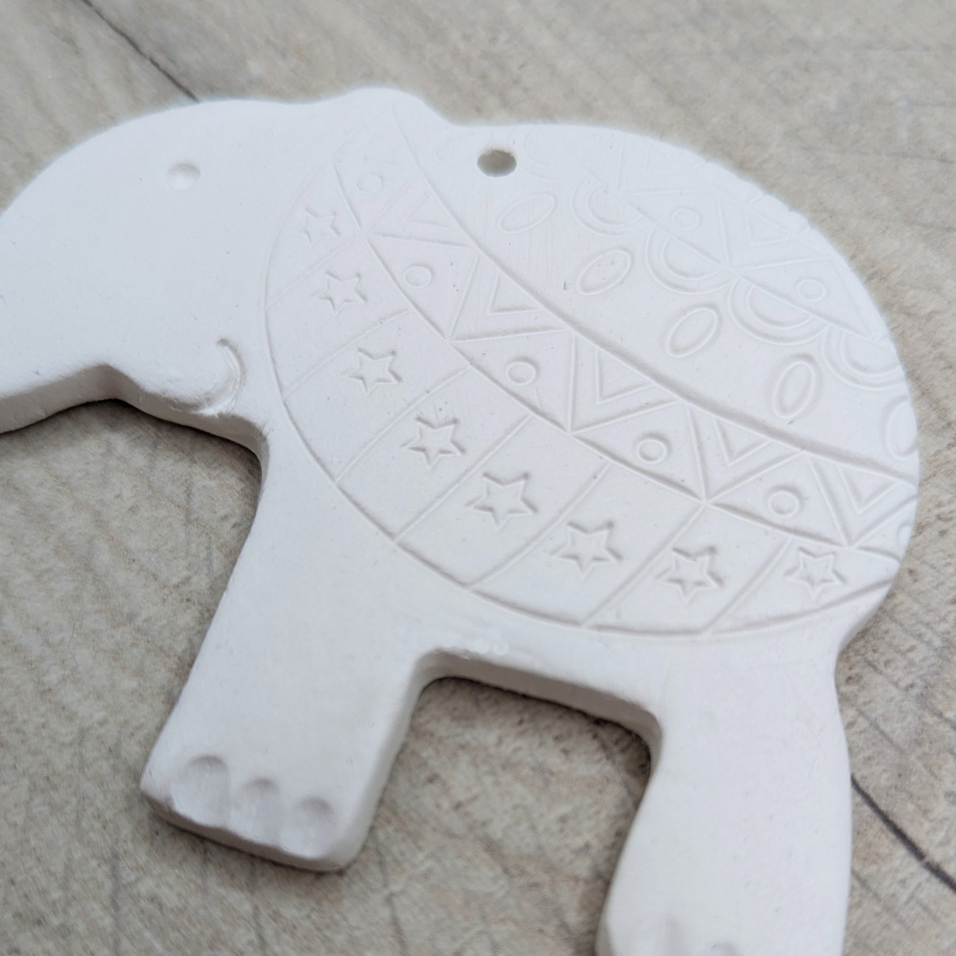 close up of adult elephant made of clay, with a pattern stamped into the back end with added toe nails, eye and mouth details