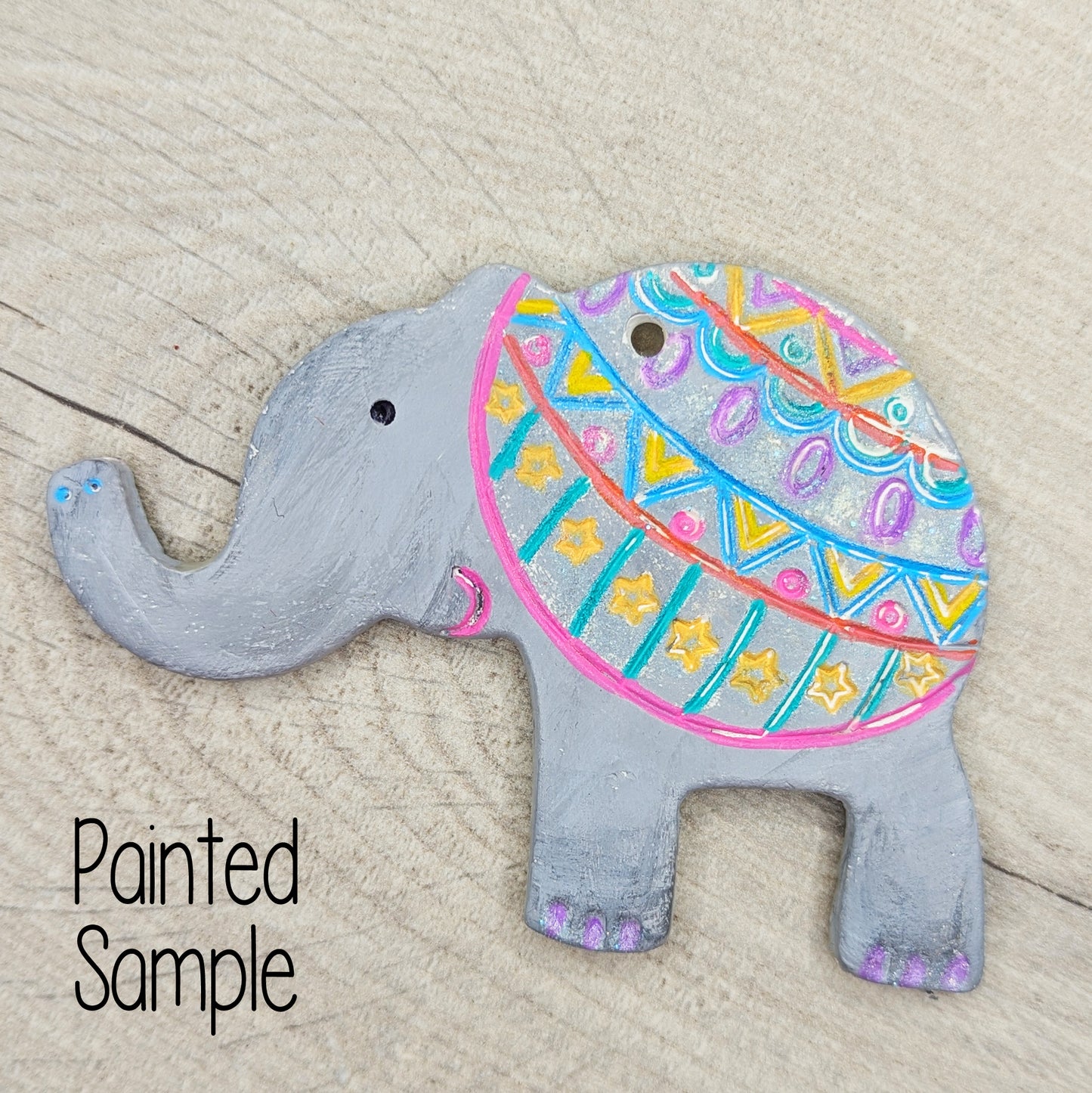 elephant decoration painted in grey with a pink, blue and yellow pattern over the back end