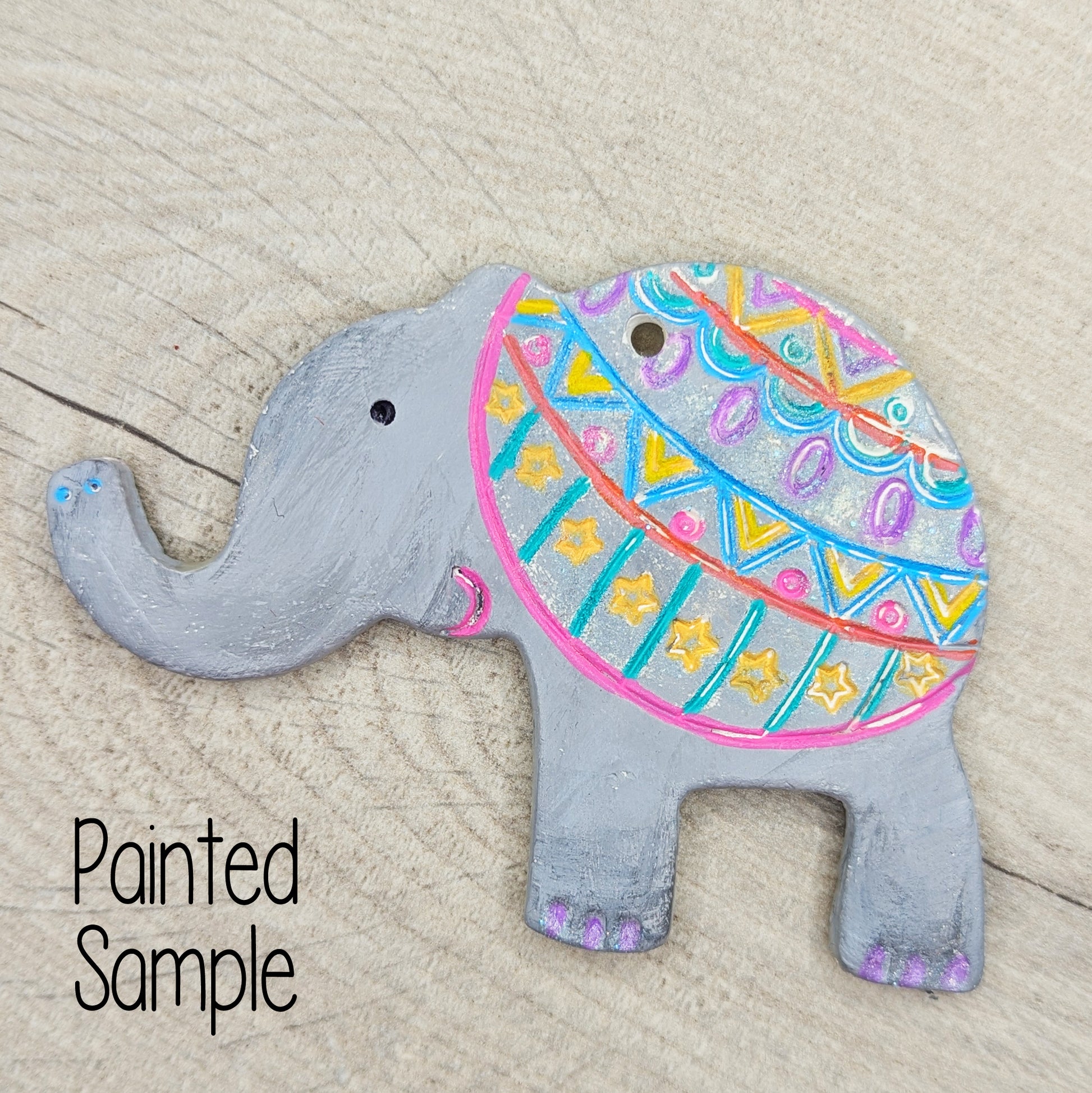 elephant decoration painted in grey with a pink, blue and yellow pattern over the back end