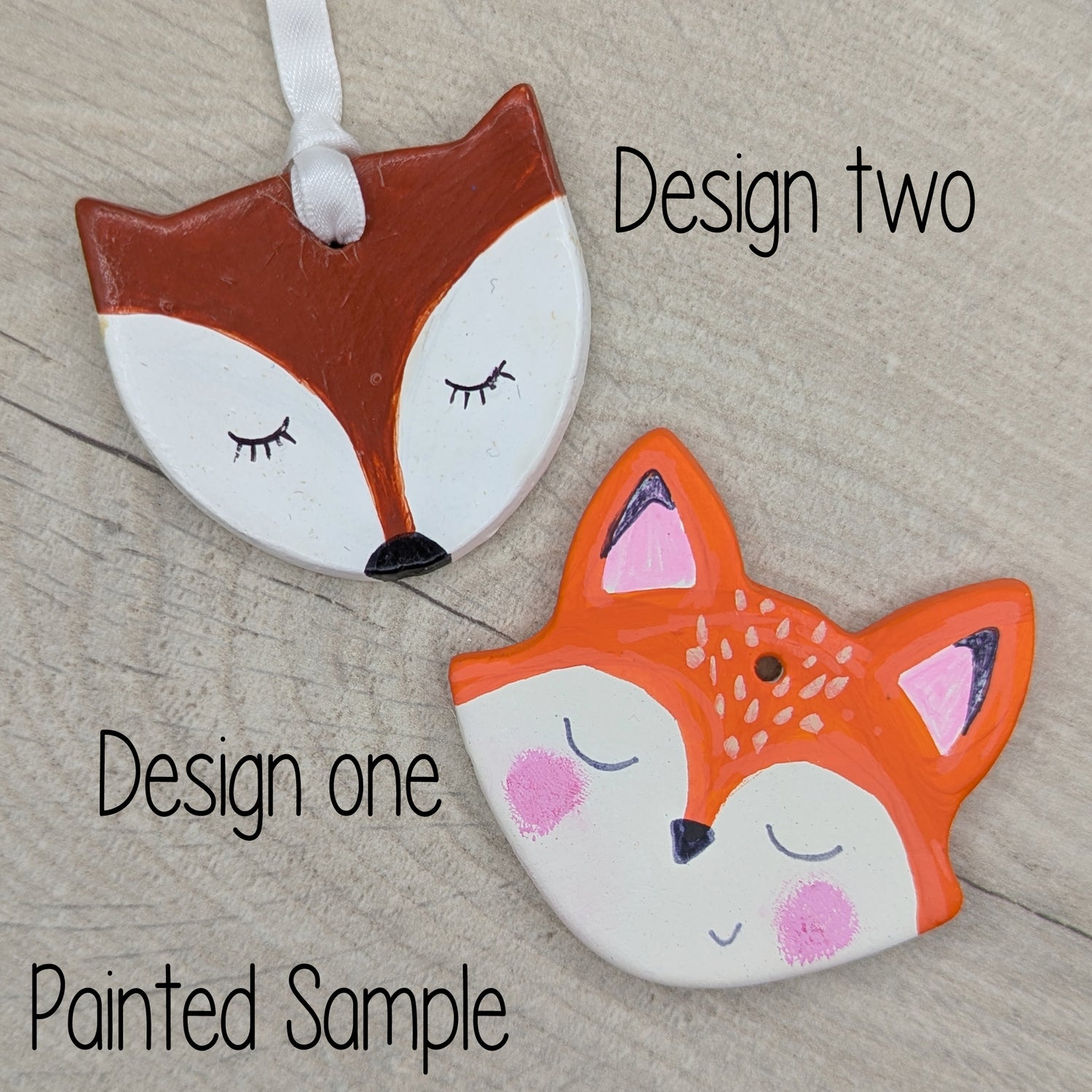 two fox heads painted in brown and white acrylic paint, one male, one female, both with facial features drawn on with sharpie