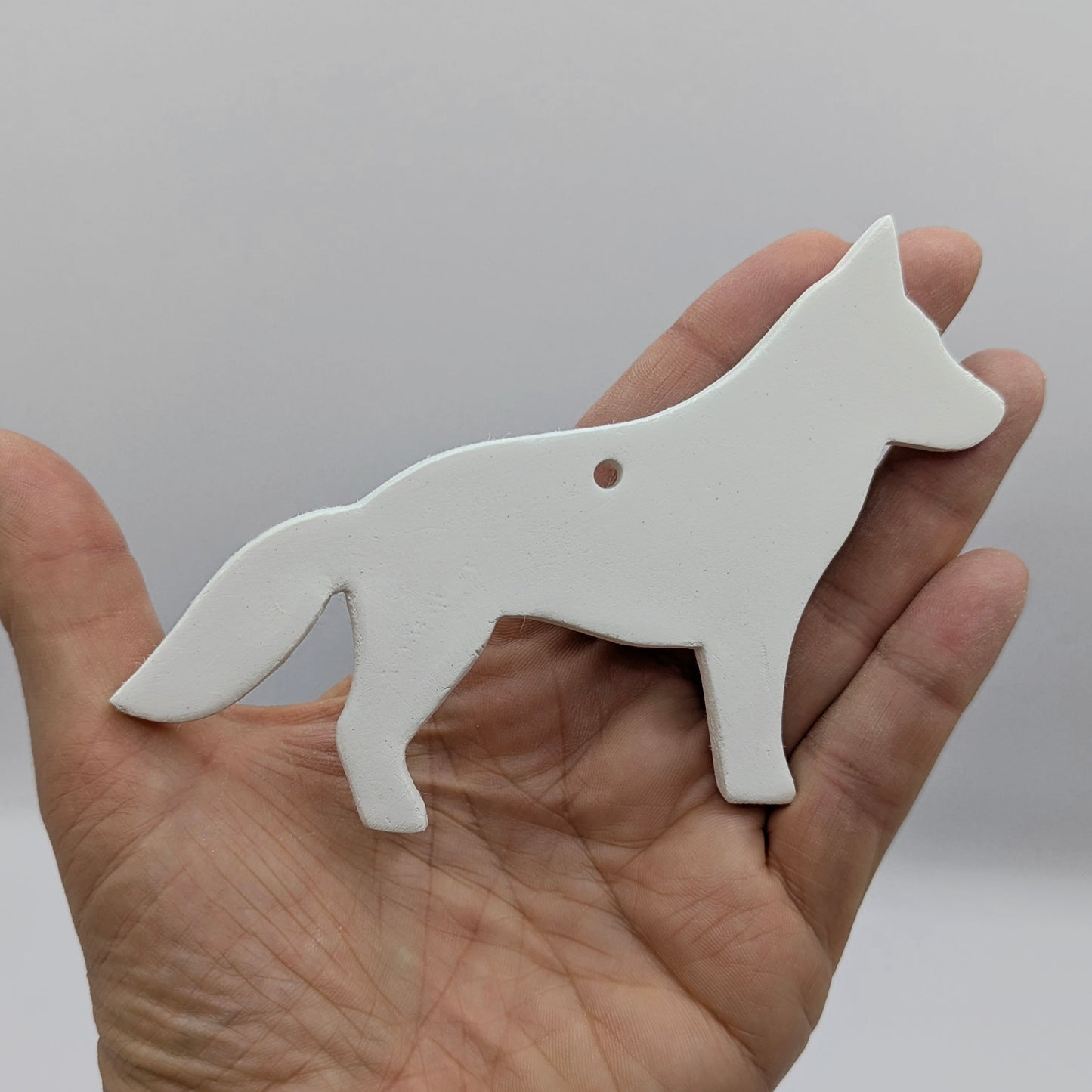 German shepherd dog shaped clay decoration shown held in some ones hand for scale purposes