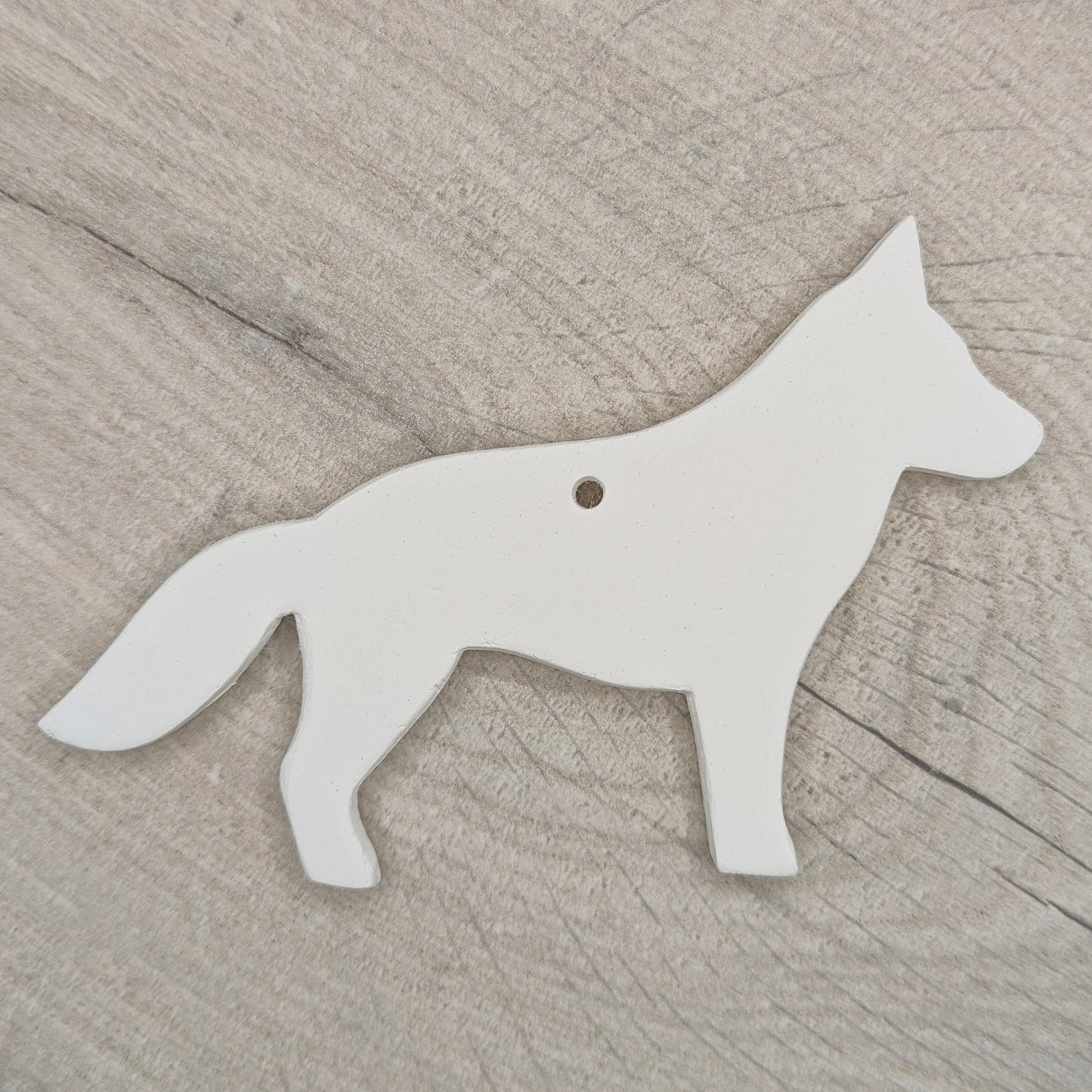 German shepherd dog shaped clay decoration shown on a light wooden background