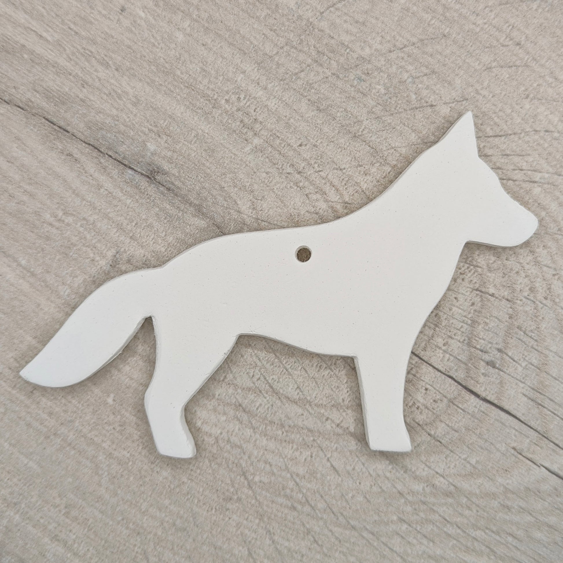 German shepherd dog shaped clay decoration shown on a light wooden background
