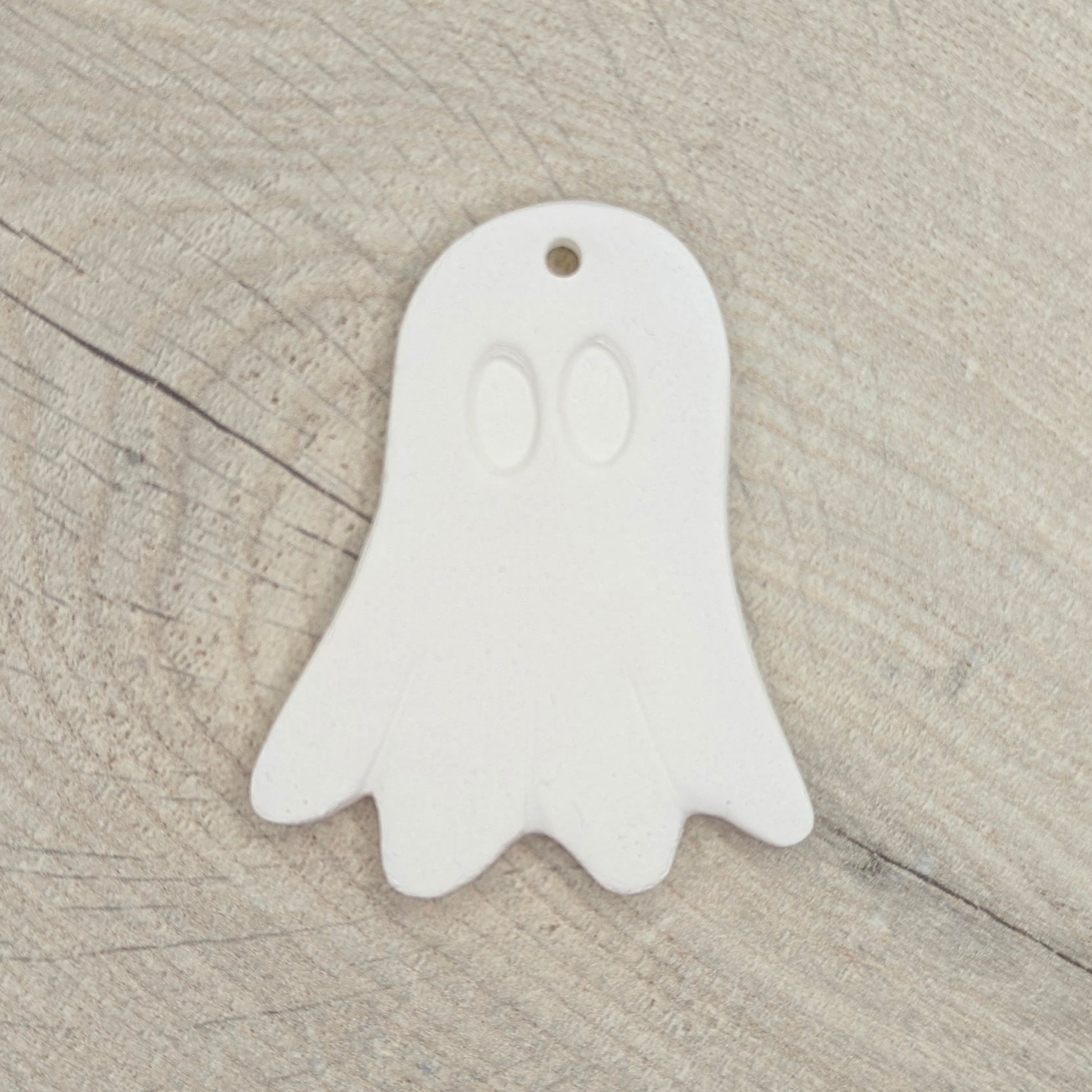 White ghost-shaped clay decoration on a wooden surface