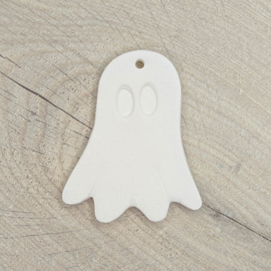 White ghost-shaped clay decoration on a wooden surface