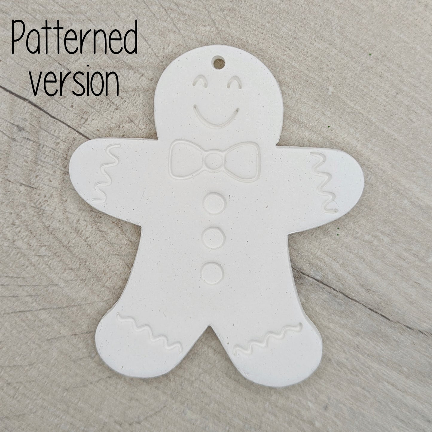 White clay gingerbread man ornament, with a generic gingerbread man pattern stamped into the clay, on a wooden surface