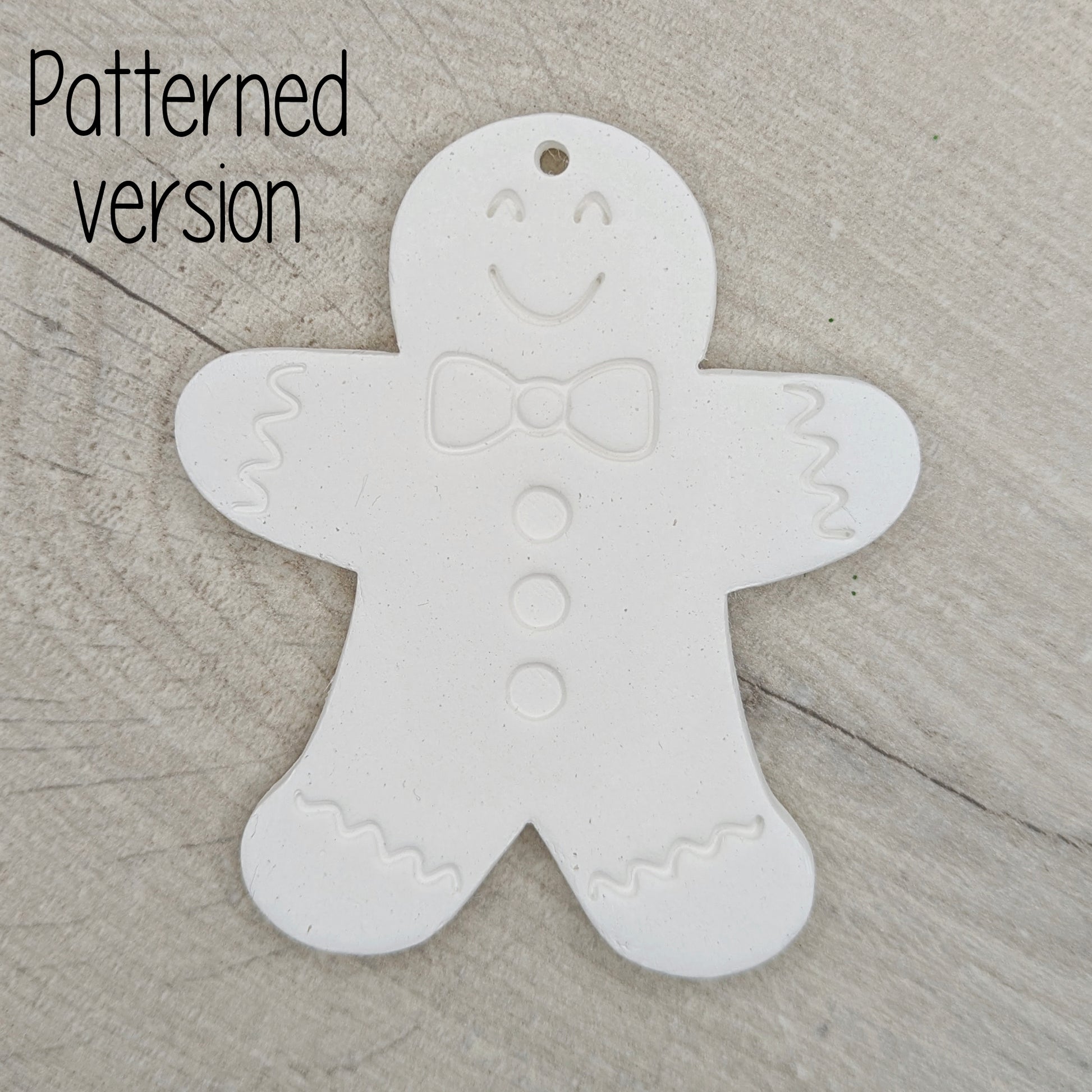 White clay gingerbread man ornament, with a generic gingerbread man pattern stamped into the clay, on a wooden surface