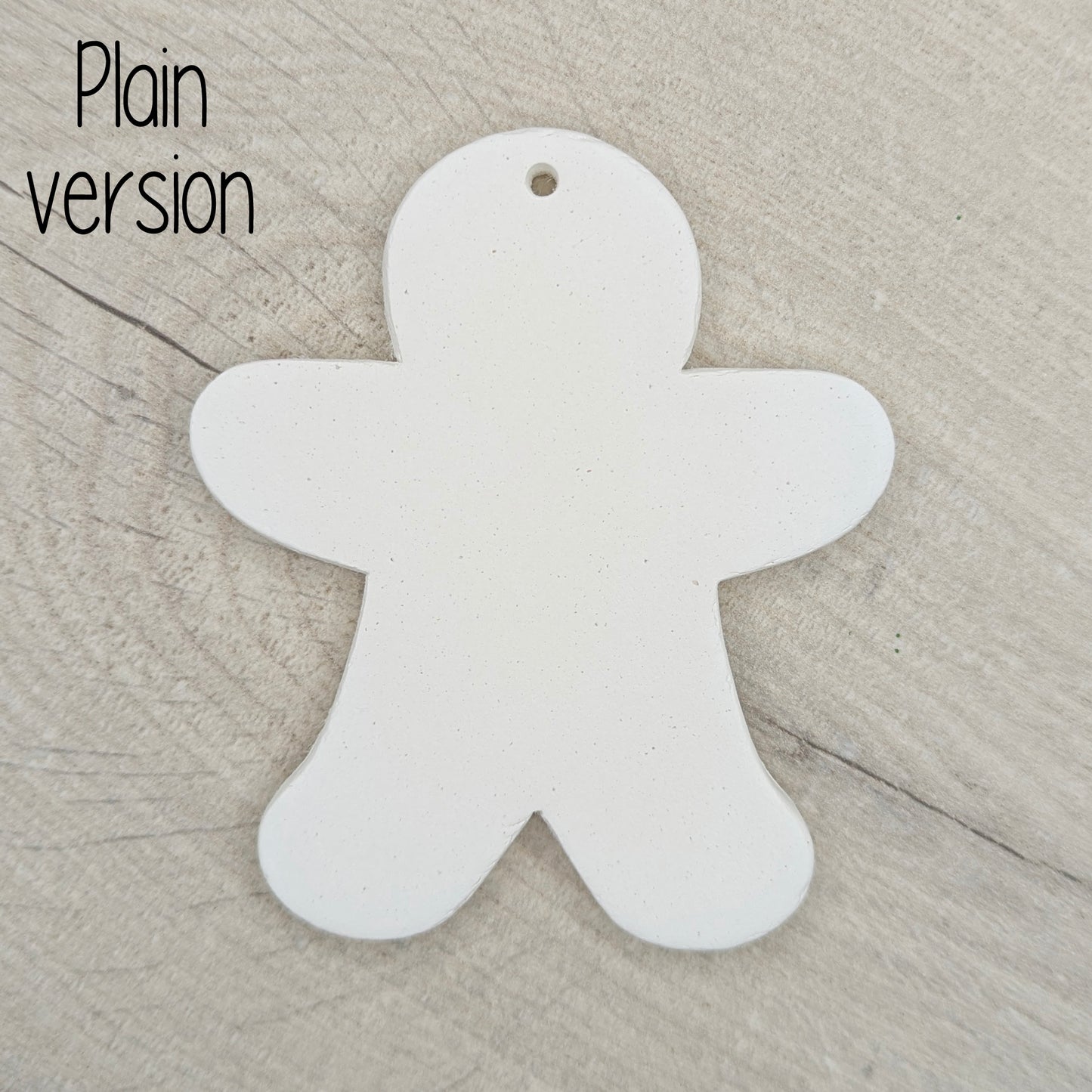 Plain white clay gingerbread man-shaped decoration on a wooden surface