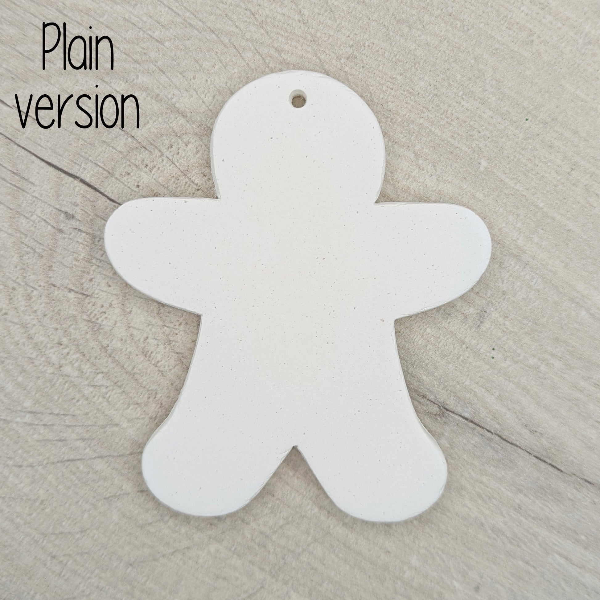 Plain white clay gingerbread man-shaped decoration on a wooden surface