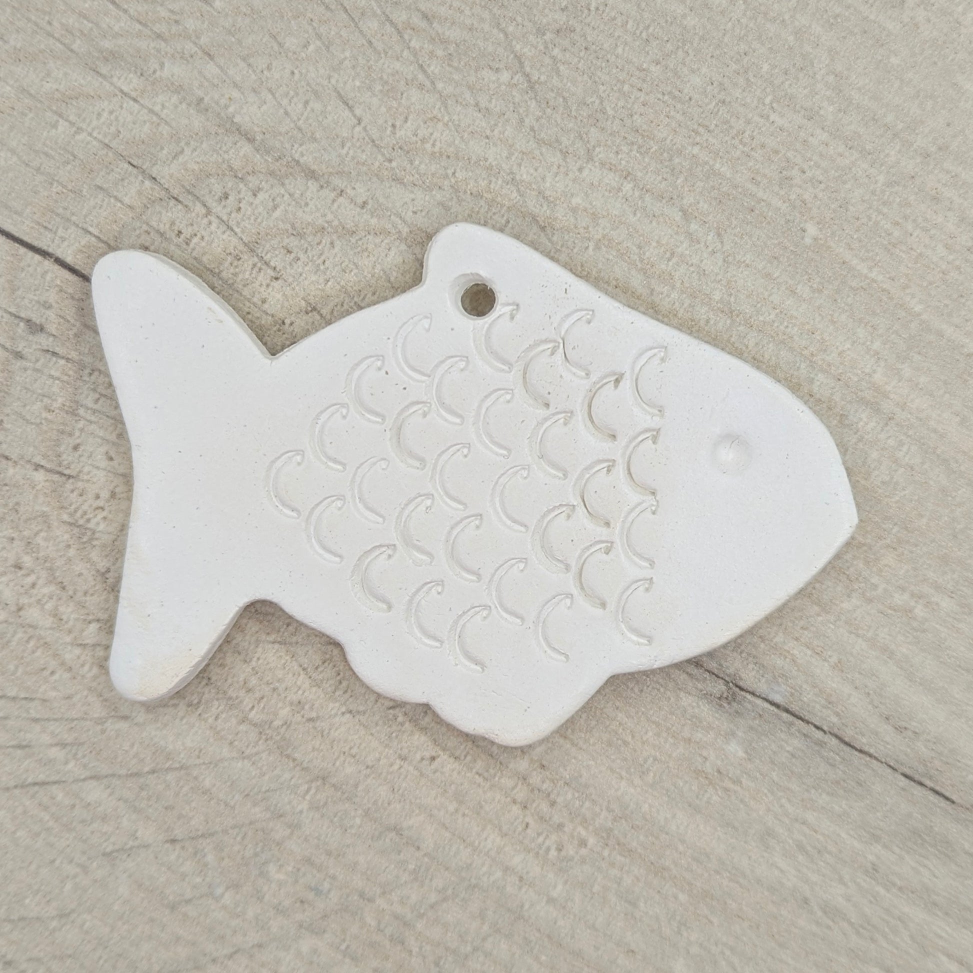 White fish-shaped clay decoration on a wooden surface