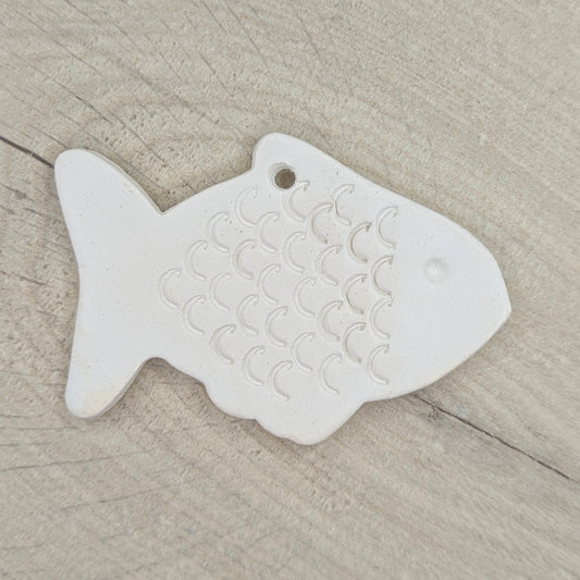 White fish-shaped clay decoration on a wooden surface