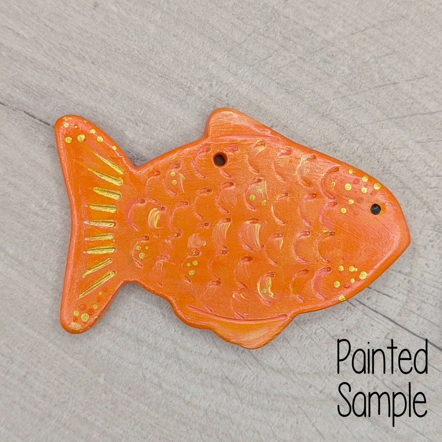 goldfish painted in orange and gold on a light brown wooden background