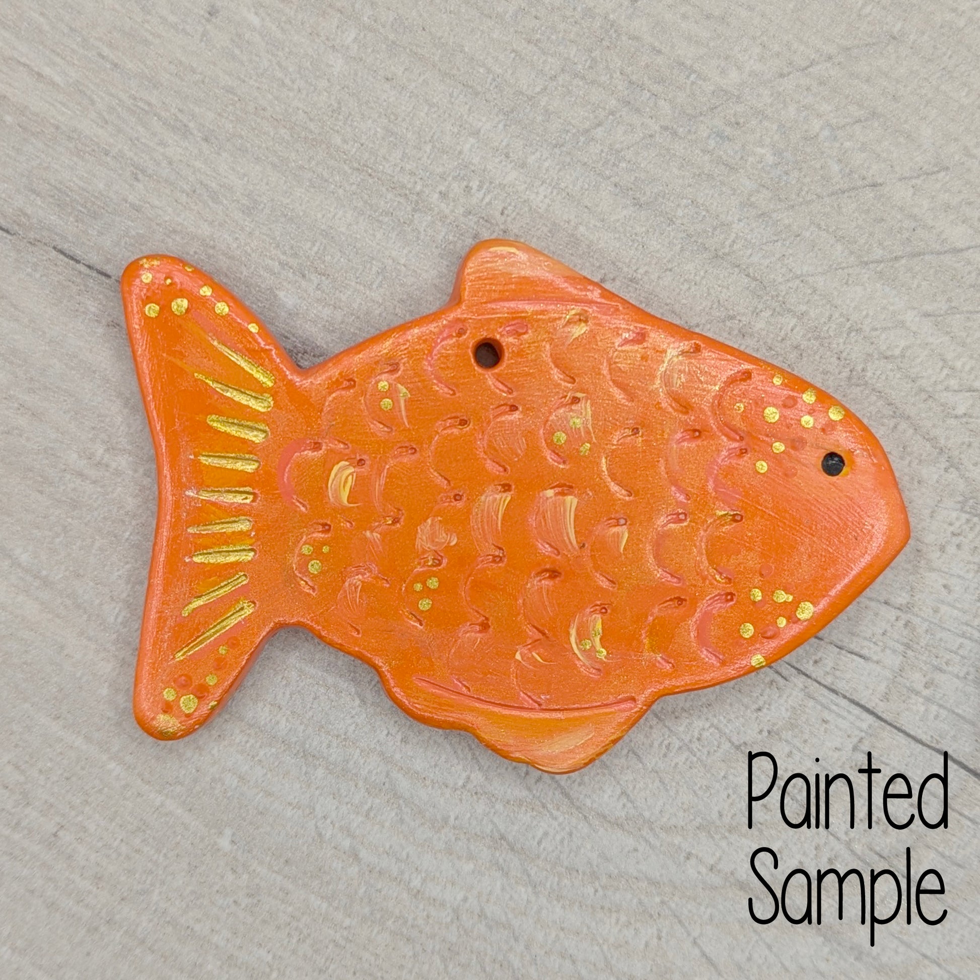 goldfish painted in orange and gold on a light brown wooden background