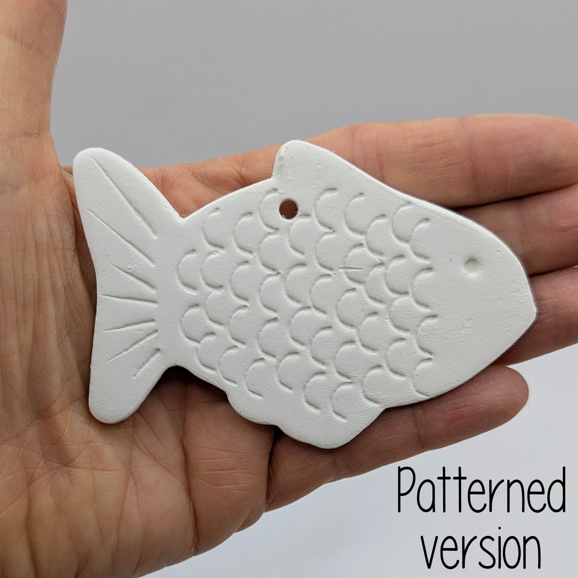 White fish-shaped clay decoration held in a hand for scale