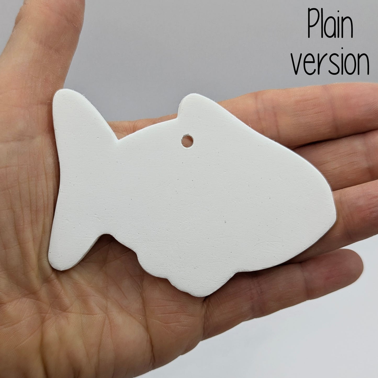 White fish-shaped clay decoration held in a hand for scale