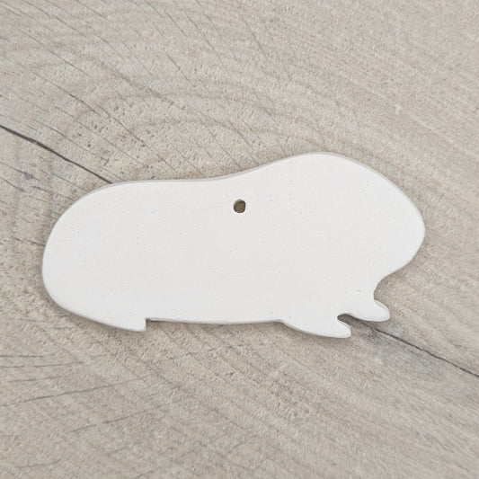 white air dried clay guinea pig shaped decoration on wooden background to paint at home