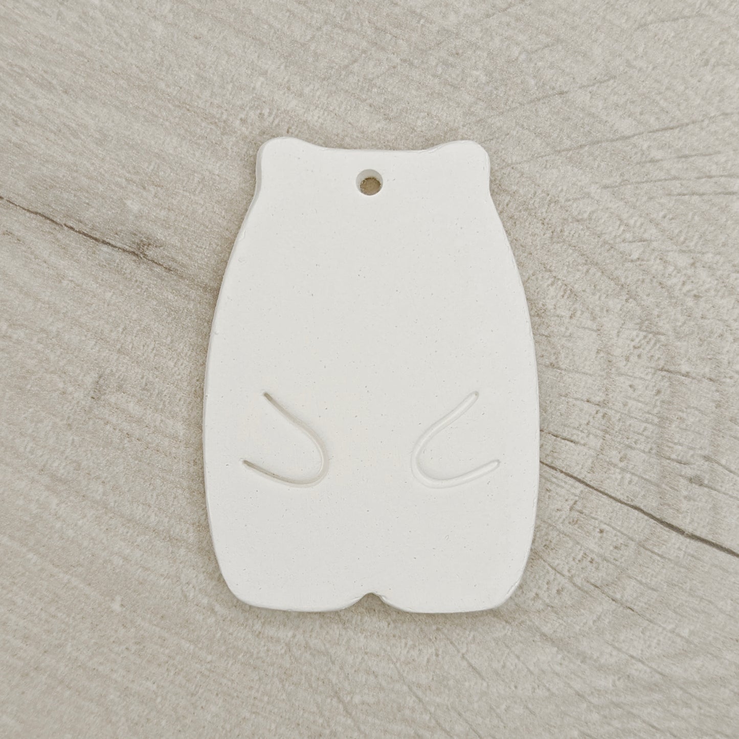 White clay hamster shaped decoration on a wooden background