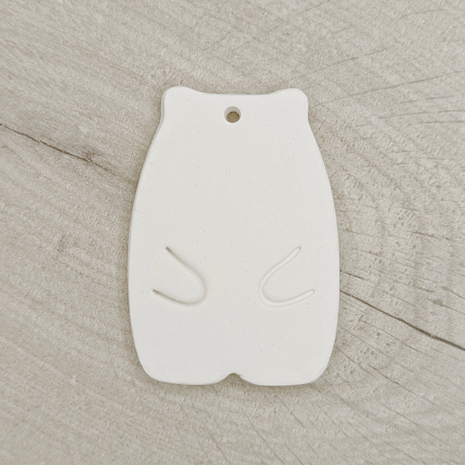 White clay hamster shaped decoration on a wooden background