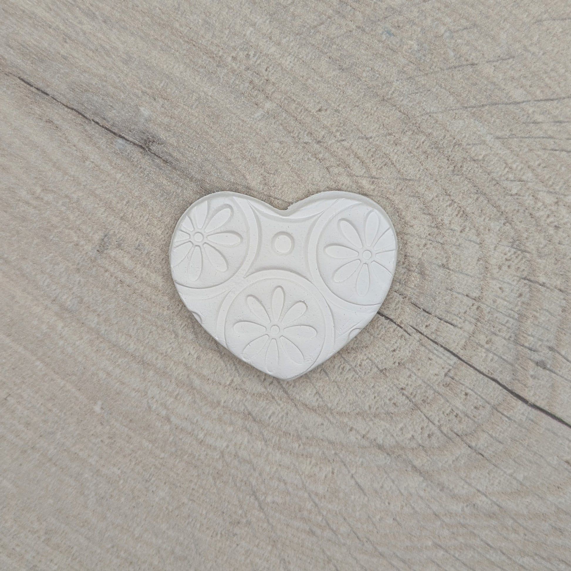 small patterned heart clay decoration displayed on wooden background
