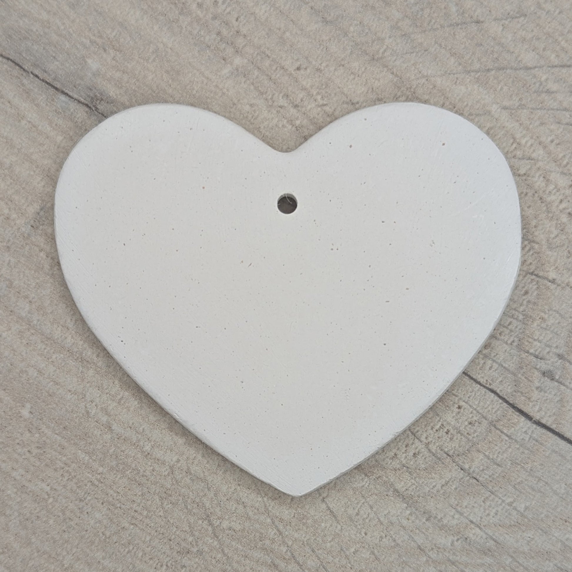 Heart shaped air dried clay decoration / tag / ornament on a wooden surface