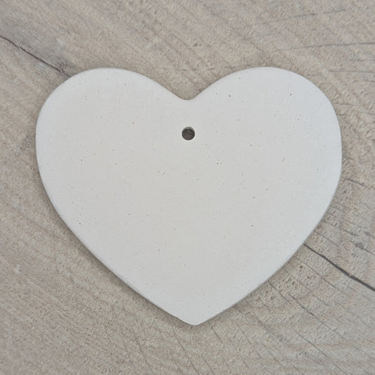 Heart shaped air dried clay decoration / tag / ornament on a wooden surface