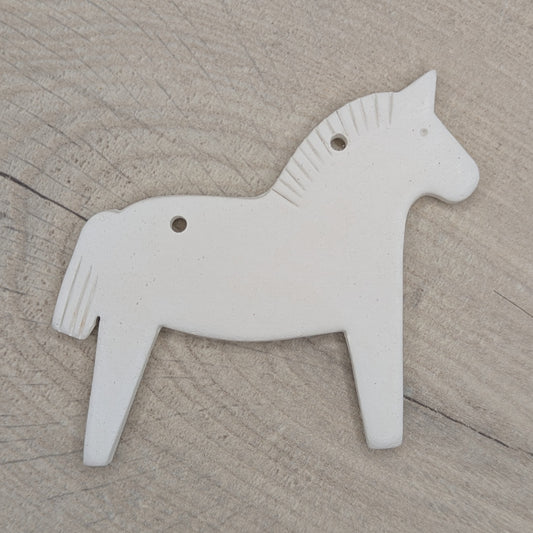 Horse shaped white clay decoration  on a wooden surface, pattern on mane and tail