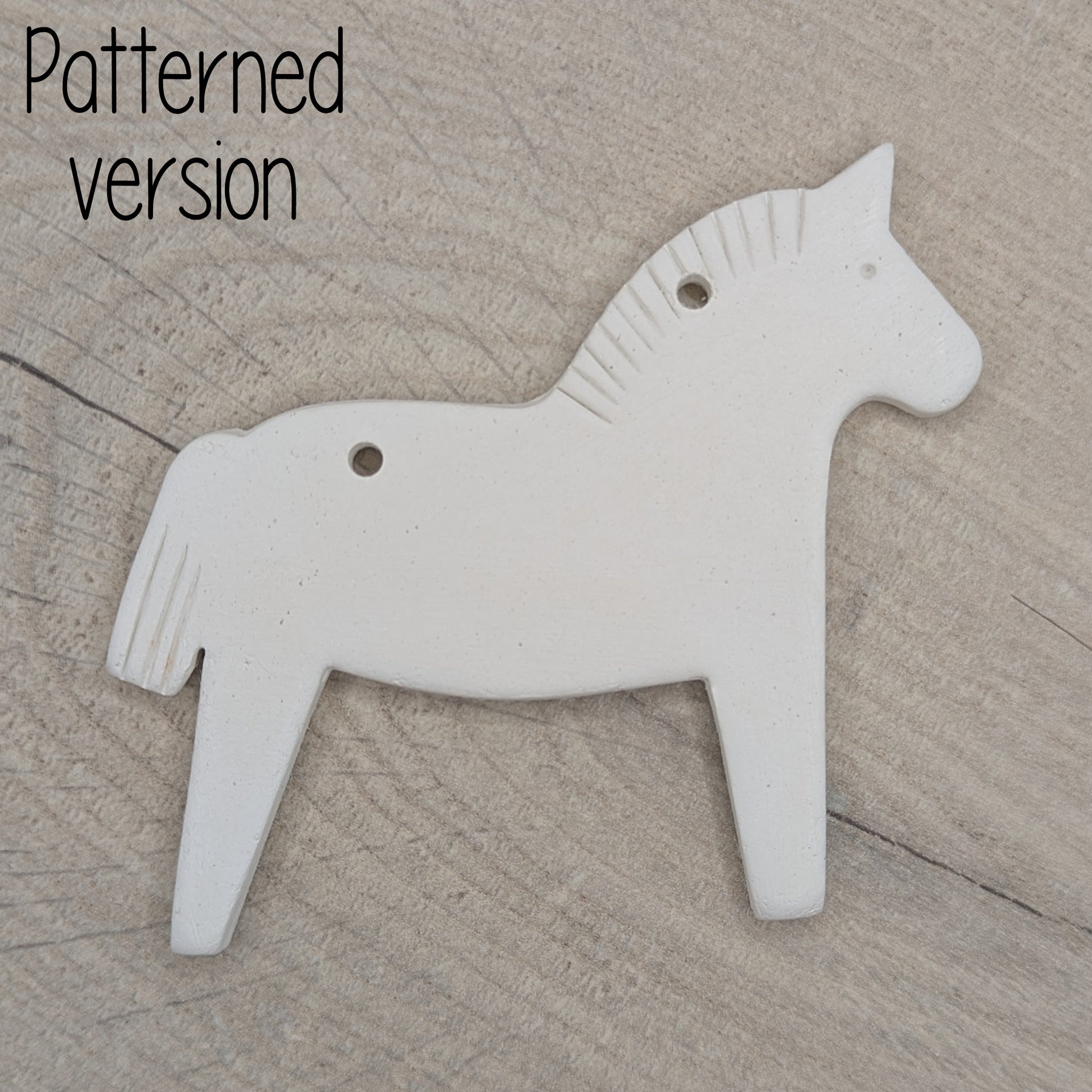 Horse shaped white clay decoration  on a wooden surface, pattern on mane and tail