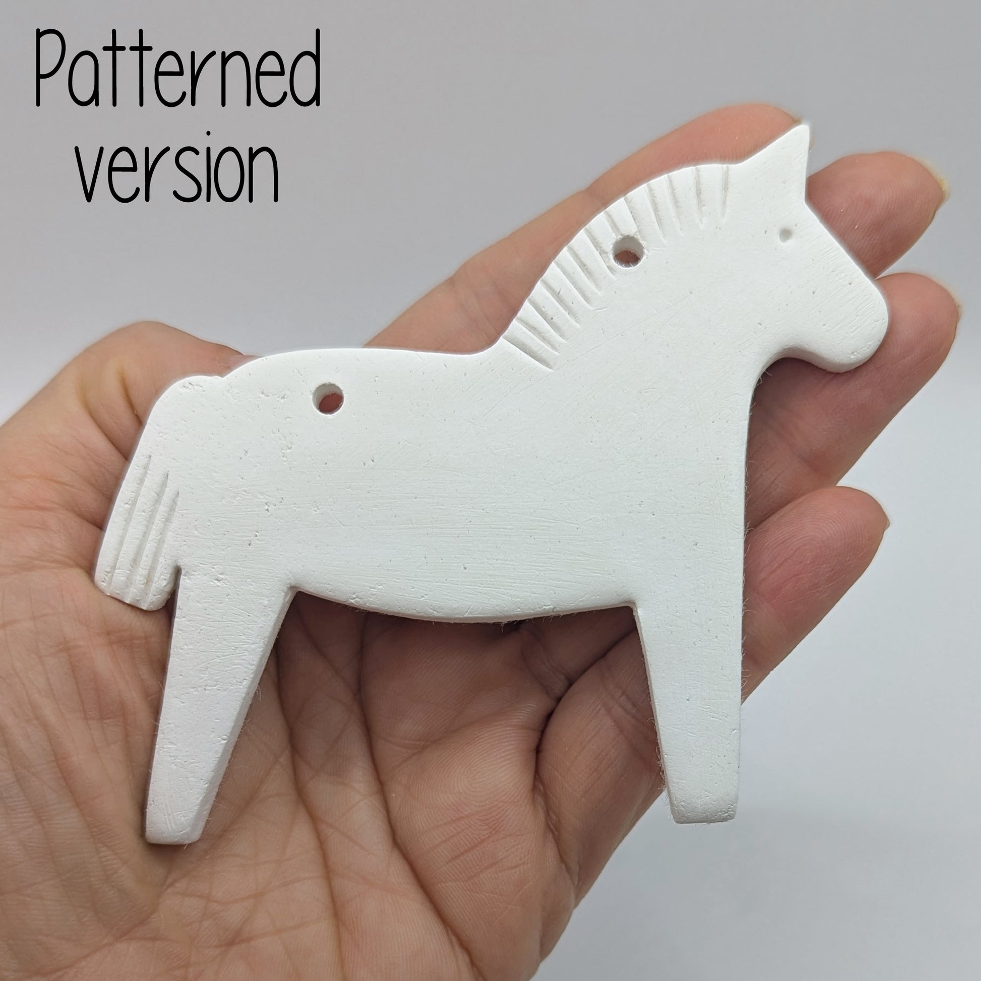 Horse shaped white clay decoration  held in hand for scale, pattern on mane and tail