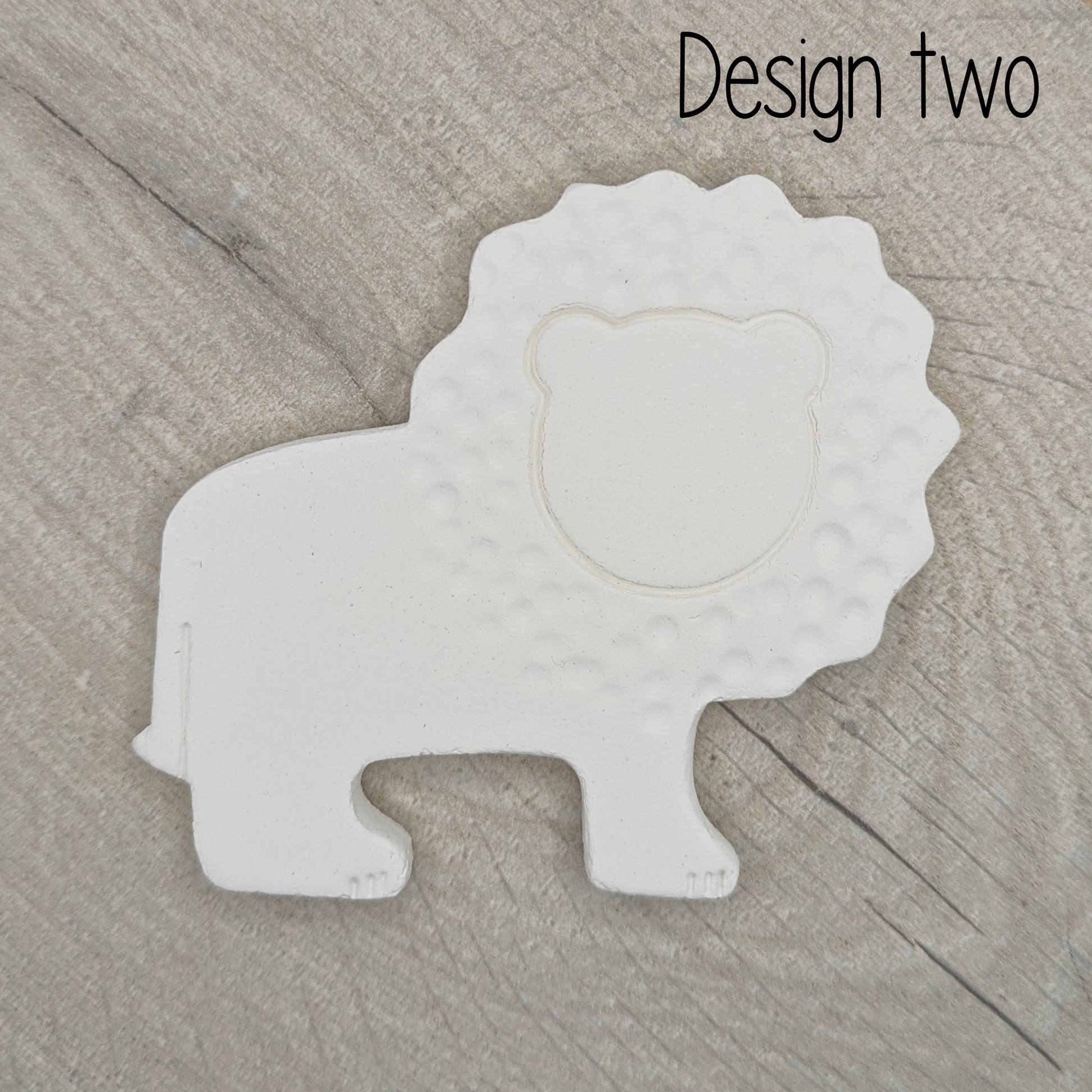 White lion-shaped decoration on a wooden surface with 'Design two' 
