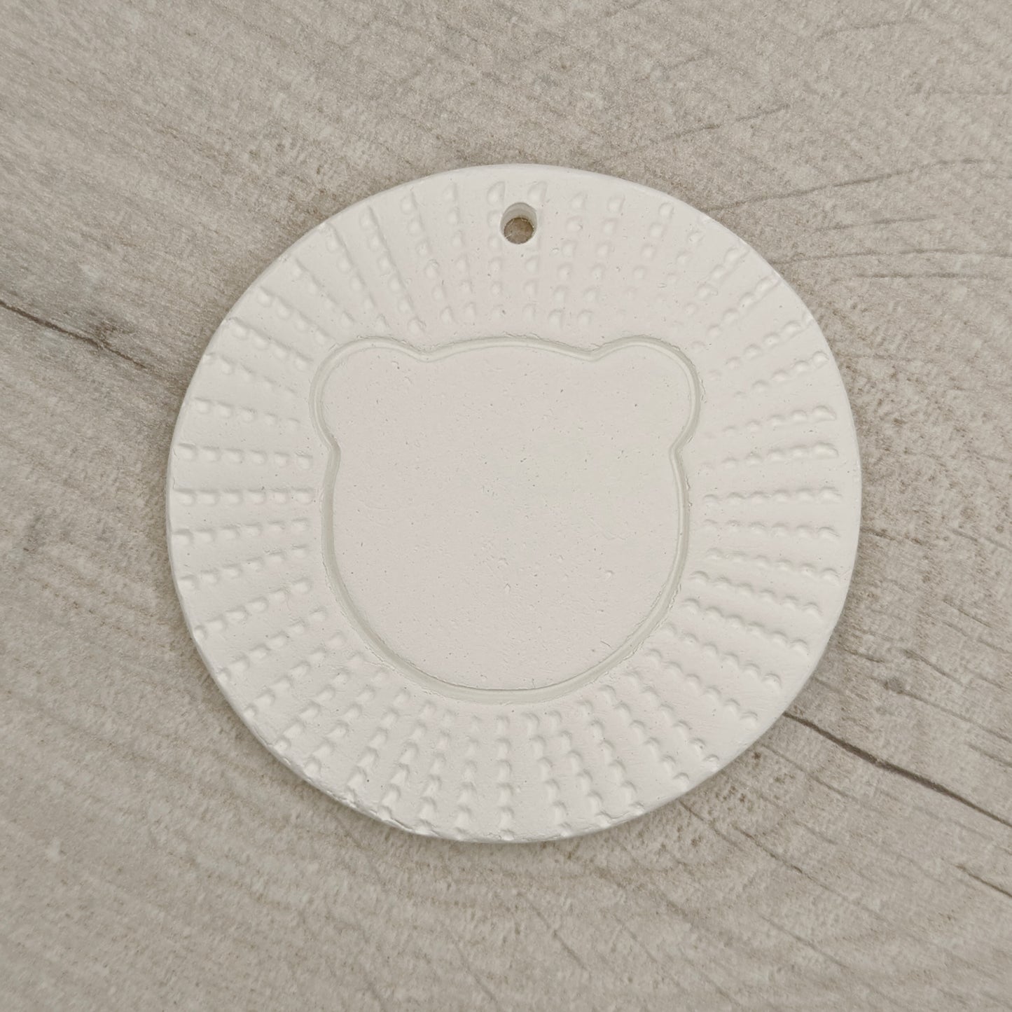 air died clay decoration in the style of a stylised lion head, on a wooden background