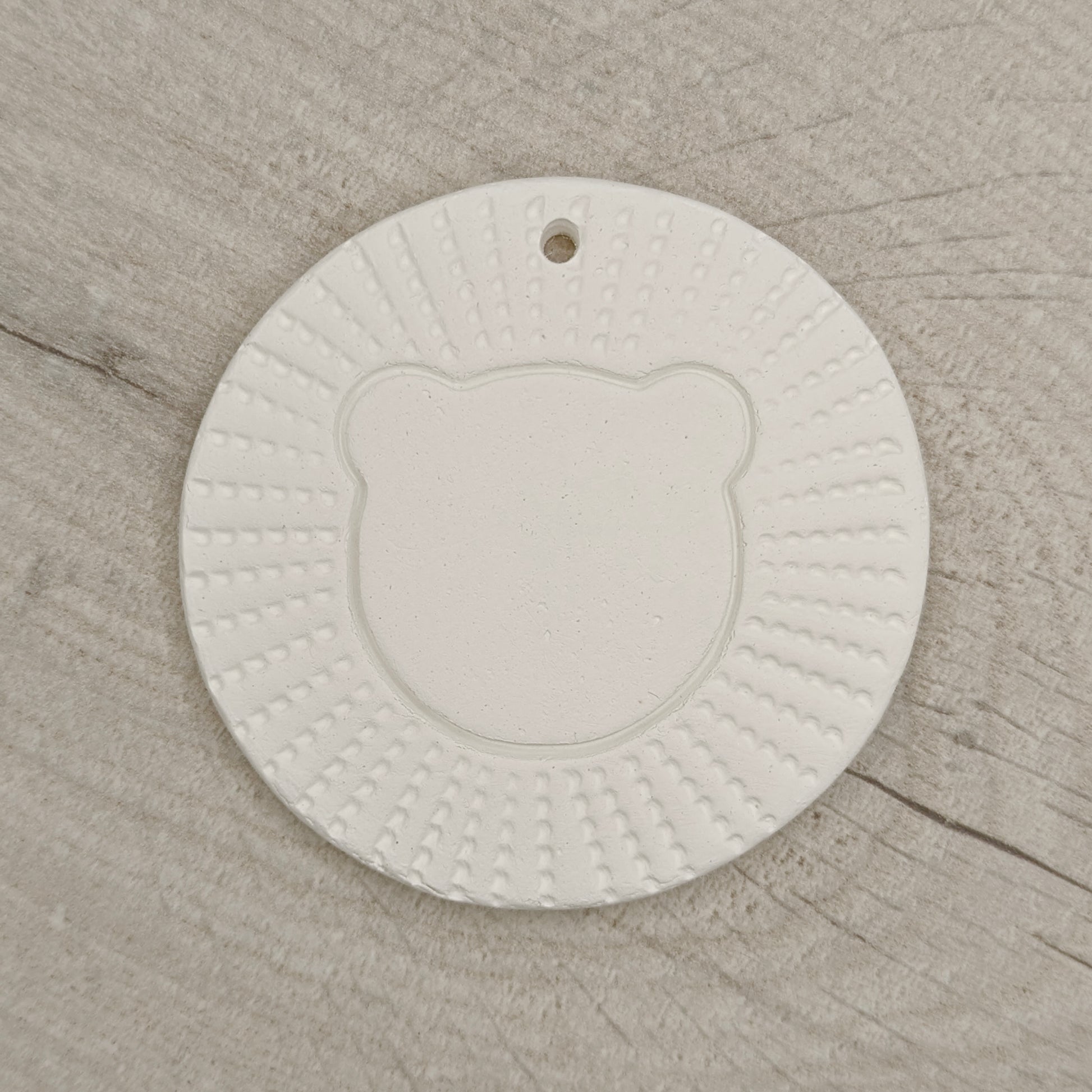 air died clay decoration in the style of a stylised lion head, on a wooden background