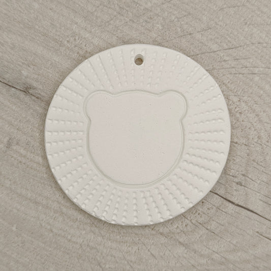 air died clay decoration in the style of a stylised lion head, on a wooden background