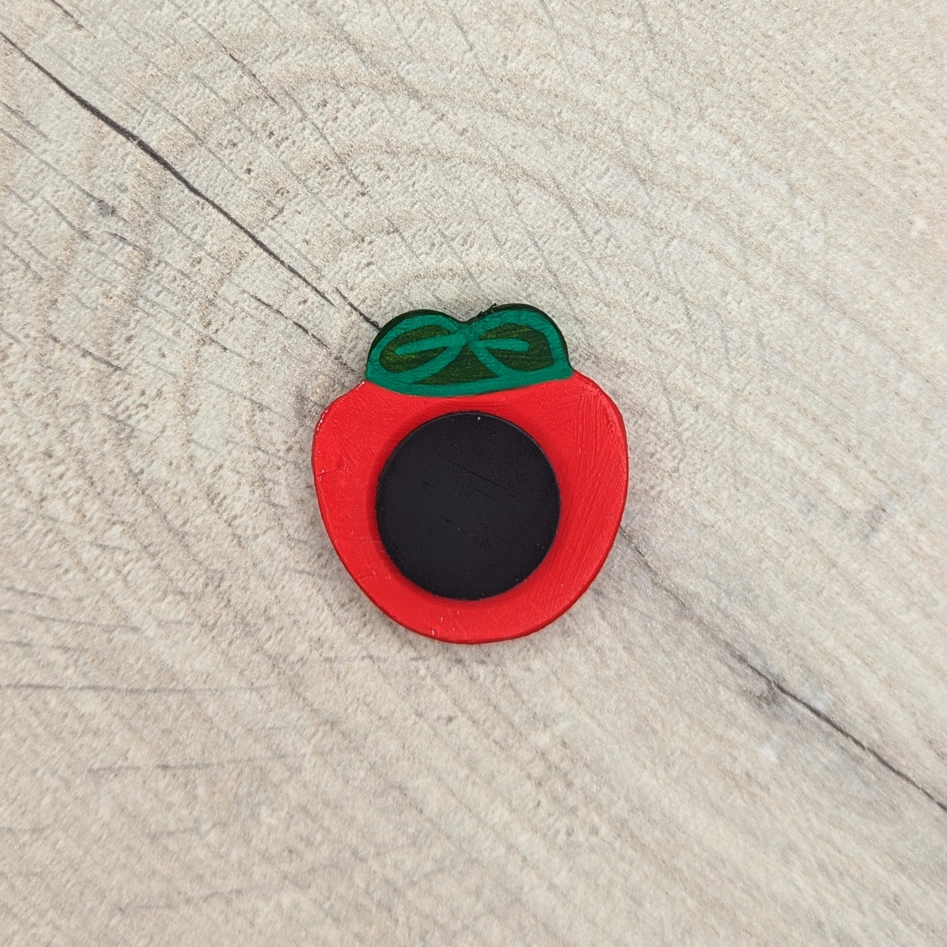 black circular magnet attached to the back of a strawberry clay decoration