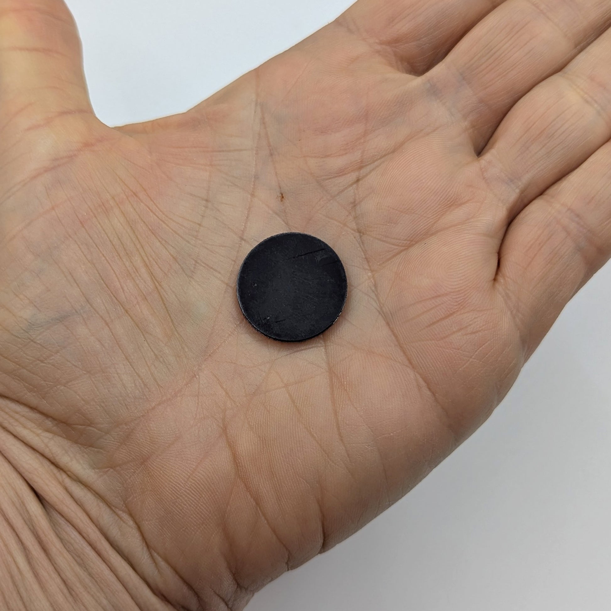 Black circular magnet on a person's palm 