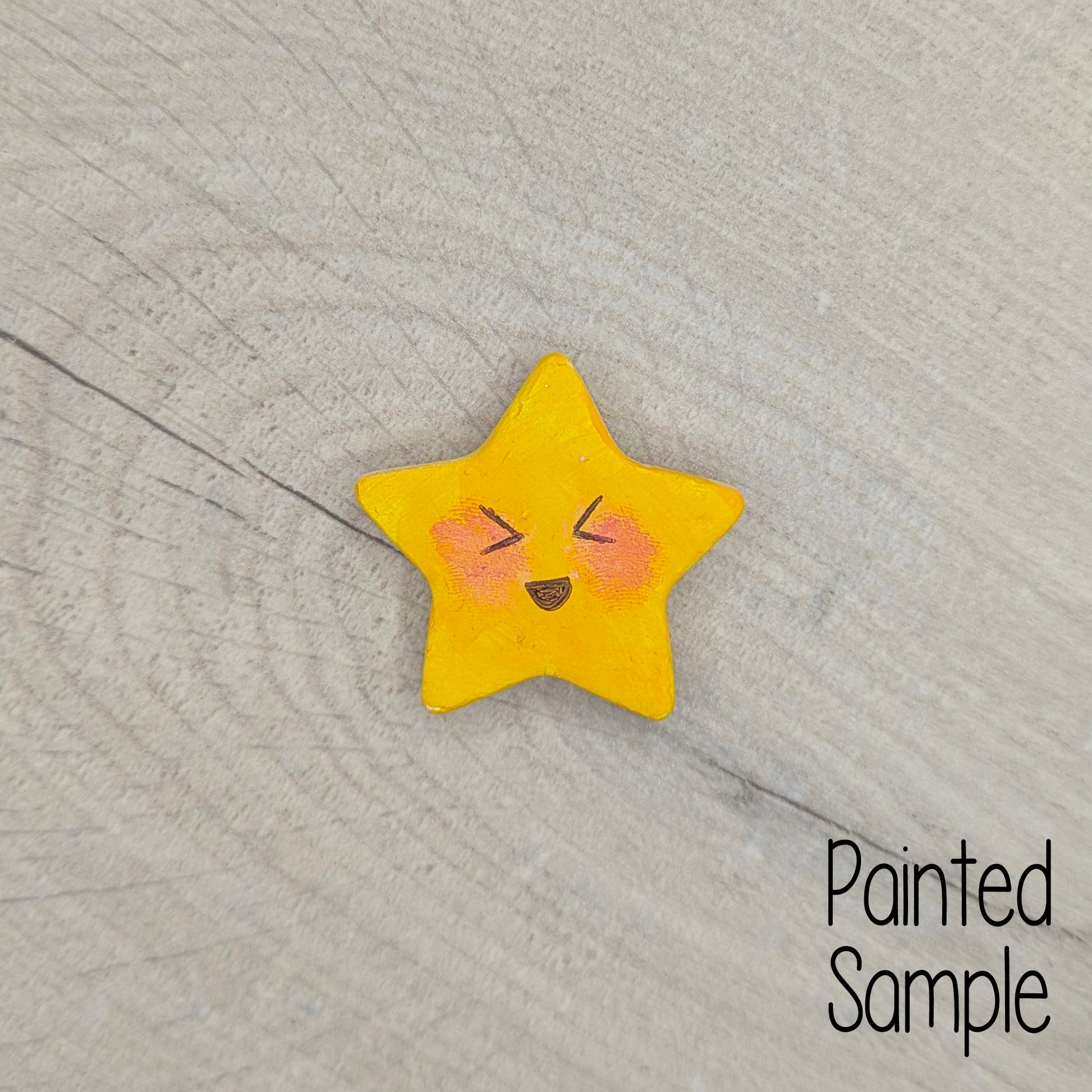Yellow painted star-shaped clay decoration with a face drawn on 