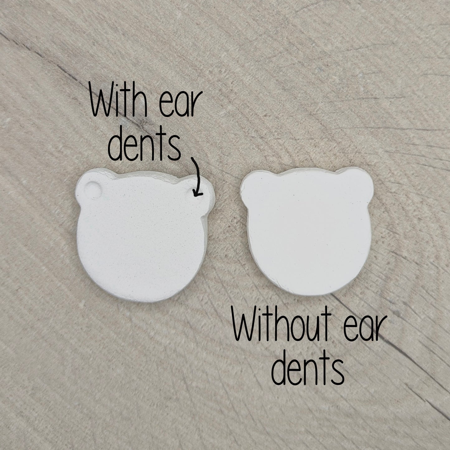 Two white bear shaped decorations on a wooden surface, labeled with 'With ear dents' and 'Without ear dents'.