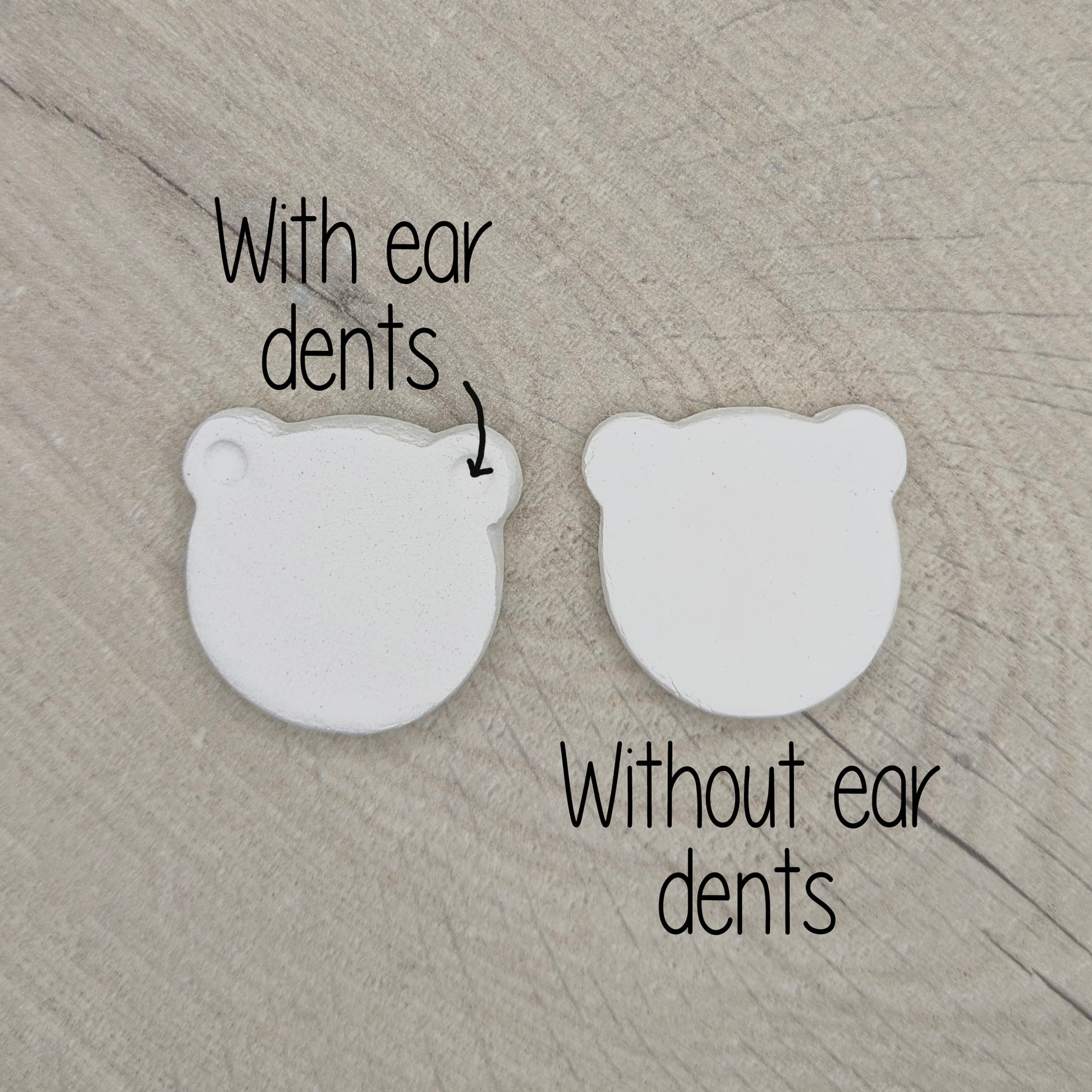 Two white bear shaped decorations on a wooden surface, labeled with 'With ear dents' and 'Without ear dents'.