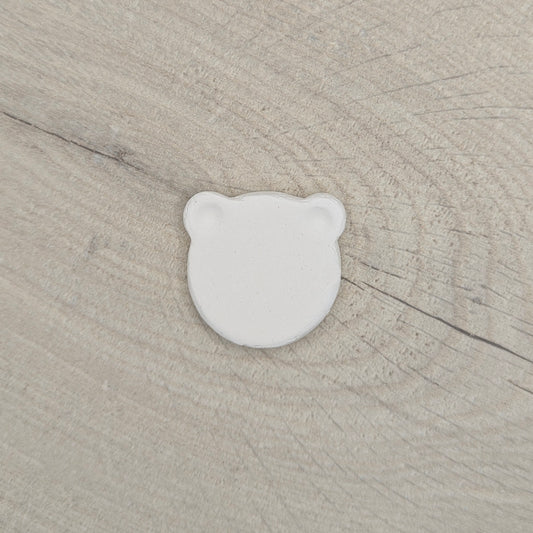 White air dried clay bear shaped decoration on a beige wooden surface