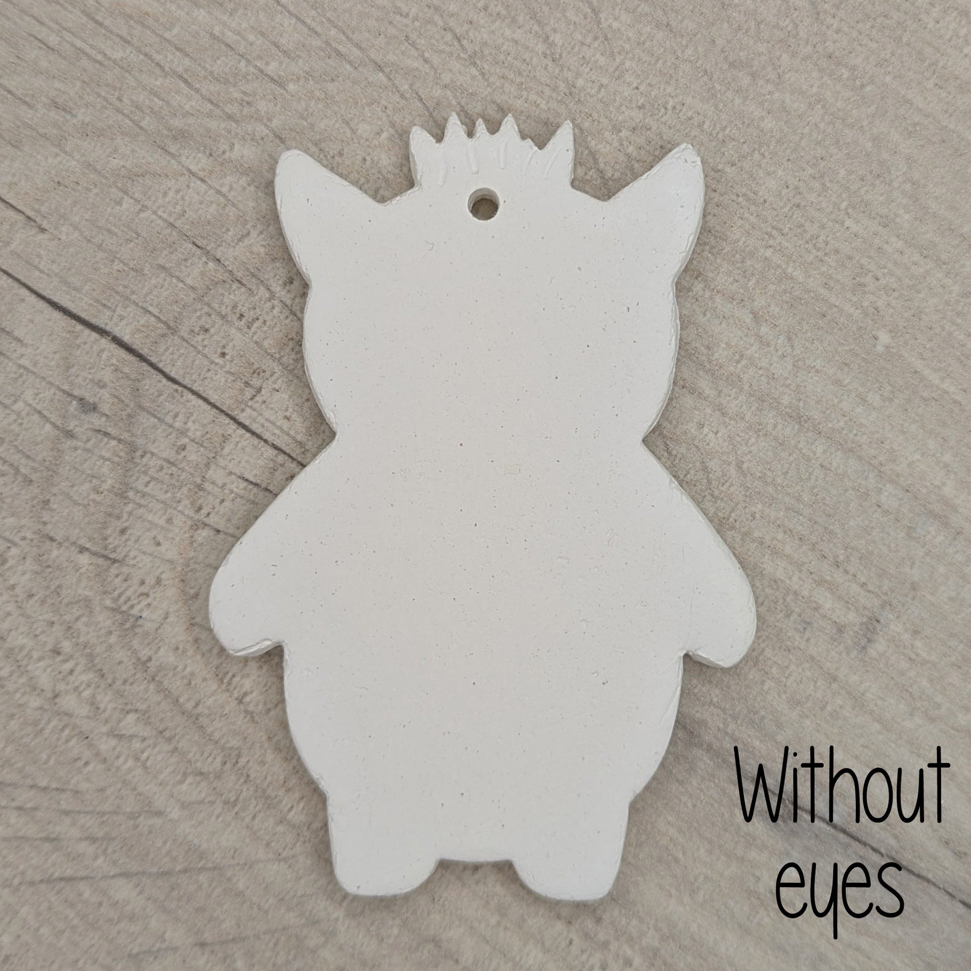 White silhouette of a funky monster with spikey hair, a pointy pair of ears on a wooden surface